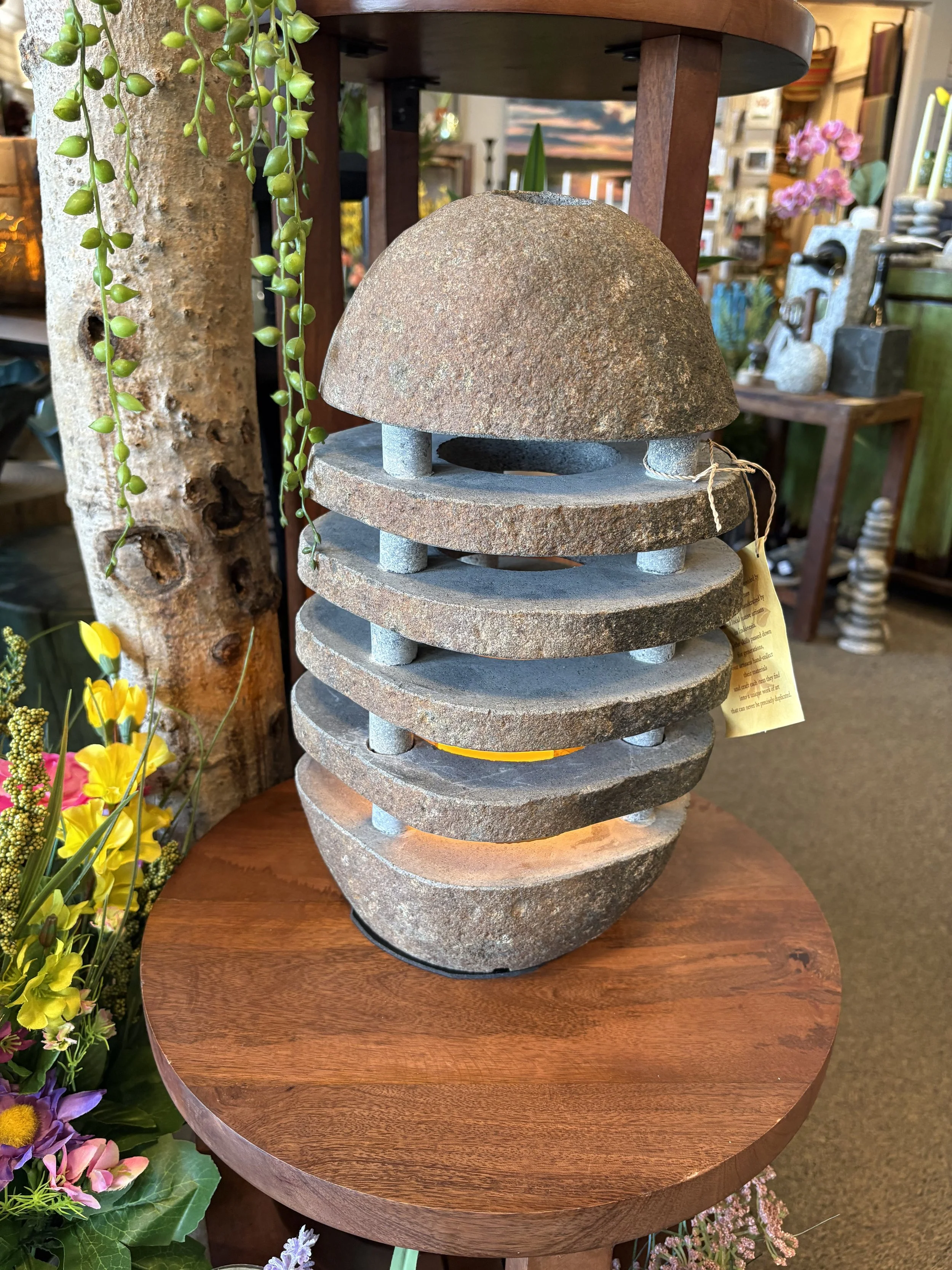 Stacked decorative stone sculptures on a wooden table with floral arrangements nearby.