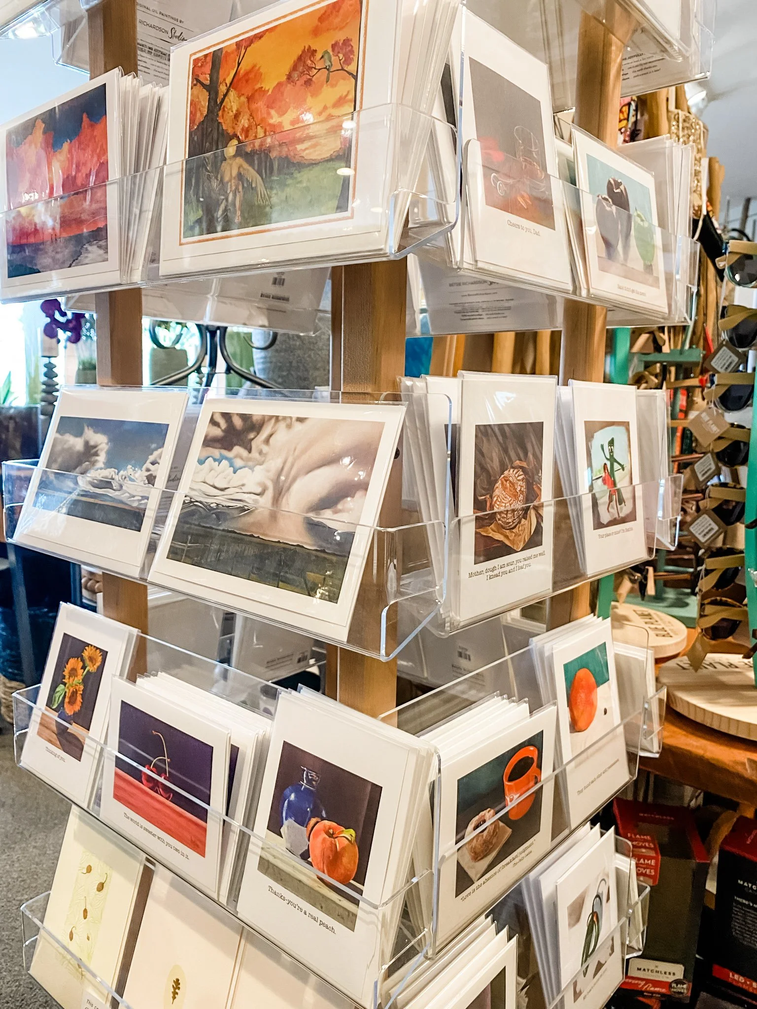A display stand featuring multiple greeting cards with various images, including landscapes, people, animals, and flowers, arranged in clear plastic pockets.