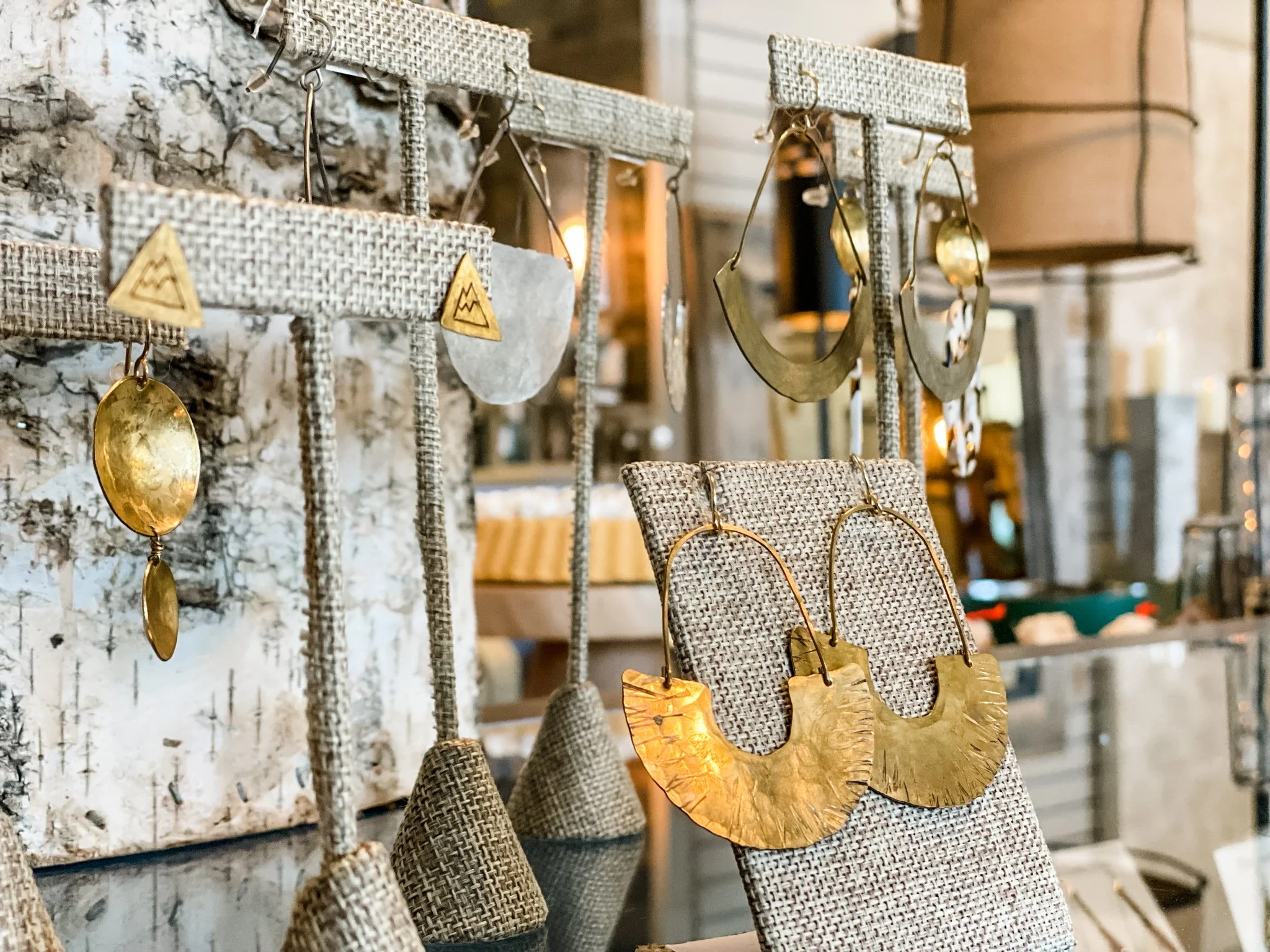 Display of various gold jewelry pieces including earrings and necklaces on fabric-covered display stands in a jewelry store.