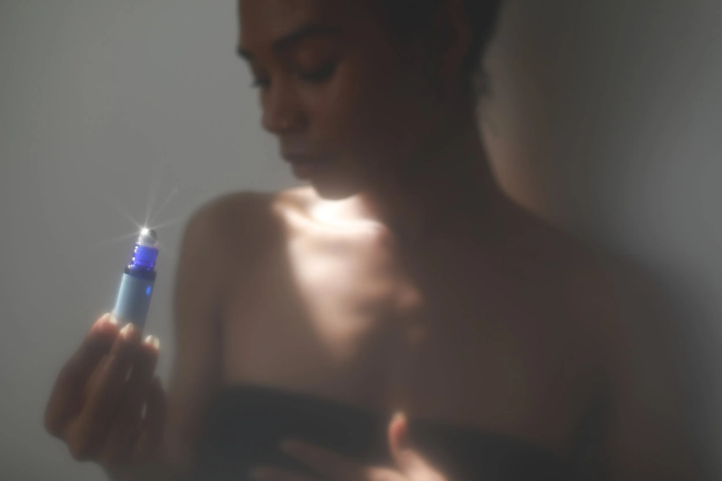 person holding Moon Time Relief roll-on cobalt glass vial
