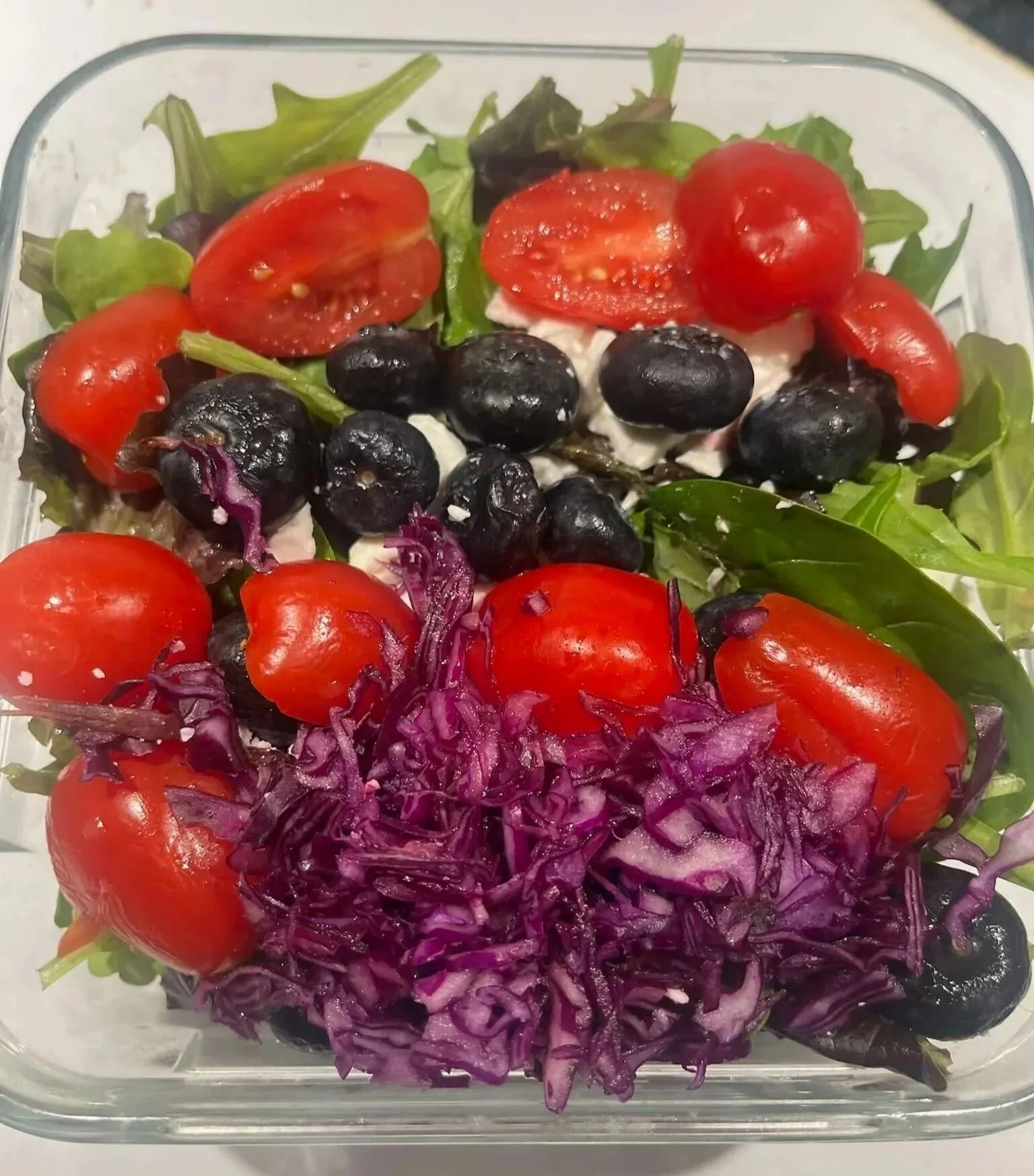 Colourful salad with leafy greens, tomatoes, blueberries and purple cabbage