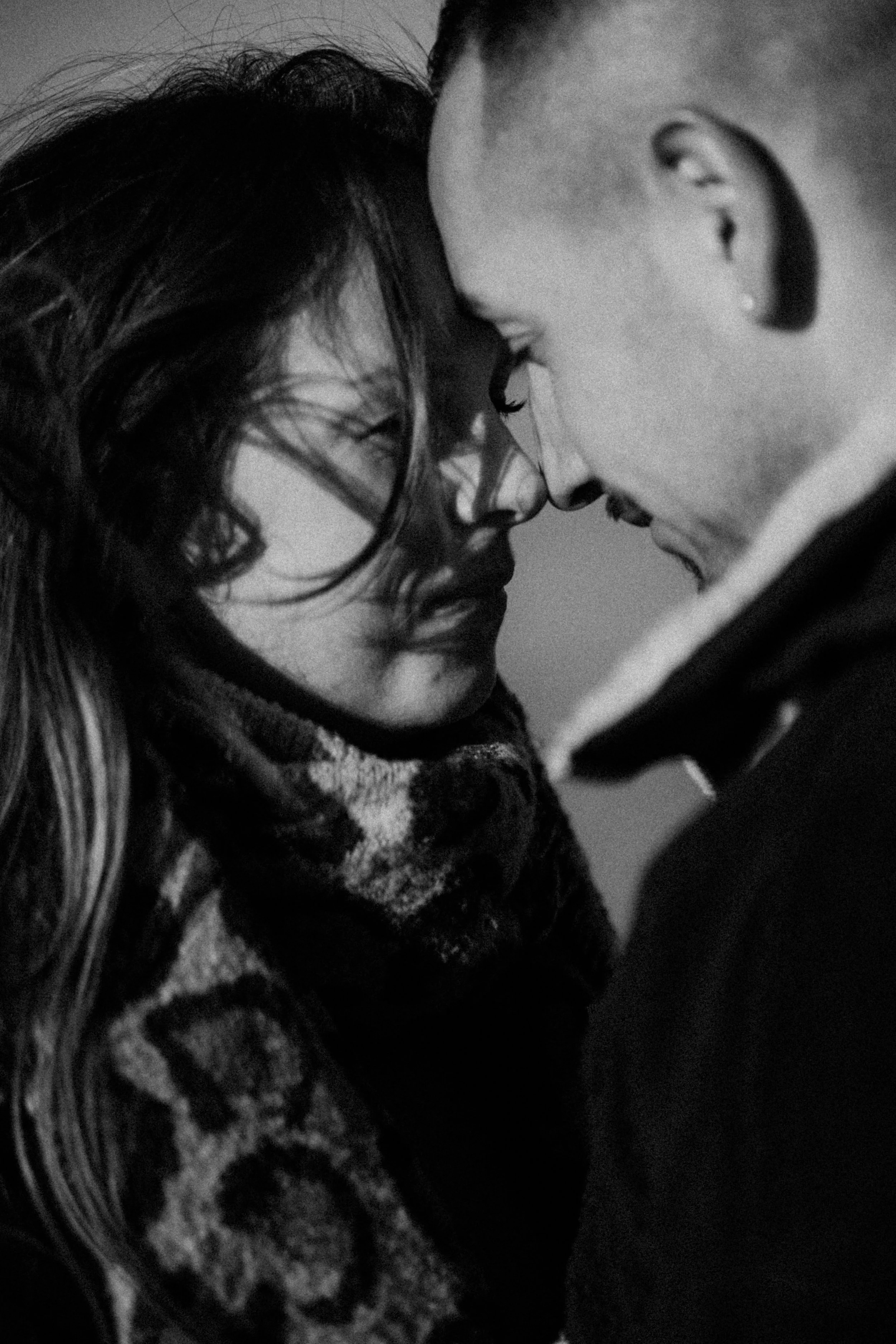 Deux personnes, un homme et une femme, très proches, touchant leurs fronts et fermant les yeux, dans une scène intime, en noir et blanc.