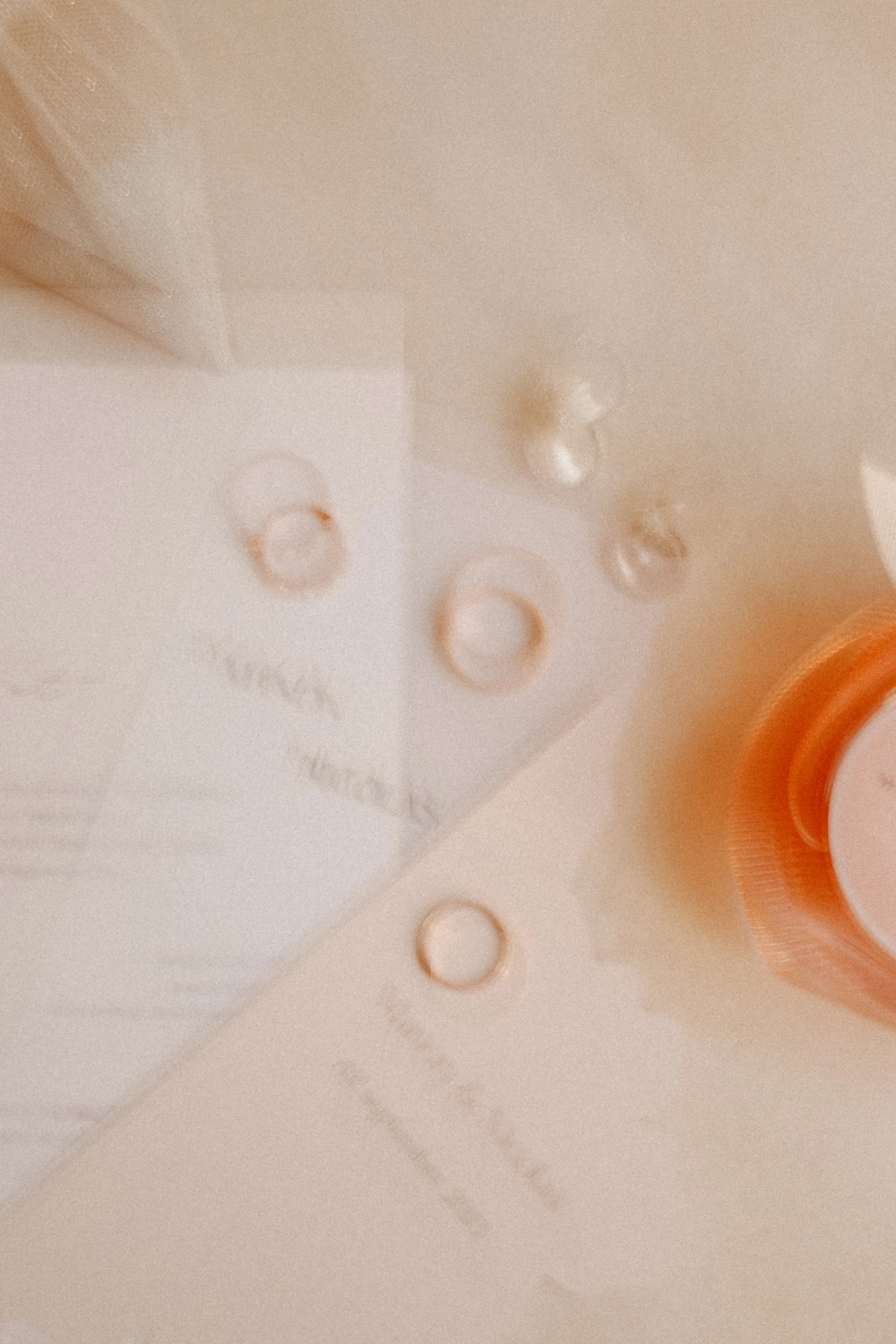 Bouteille de produit cosmétique ou pharmaceutique avec gouttes d'eau sur une surface blanche, vue de dessus avec une lumière douce.