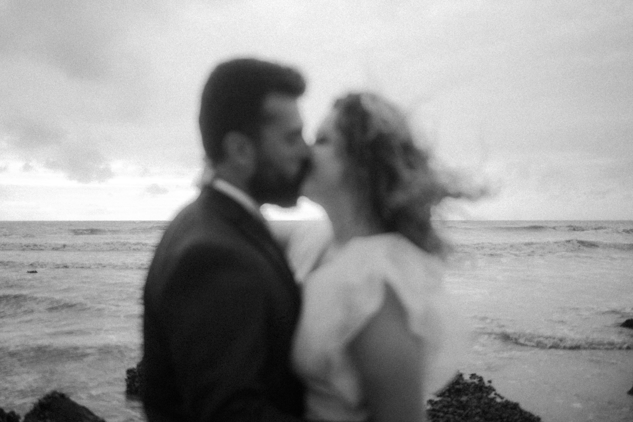 Deux personnes qui s'embrassent sur la plage, flou artistique, en noir et blanc.