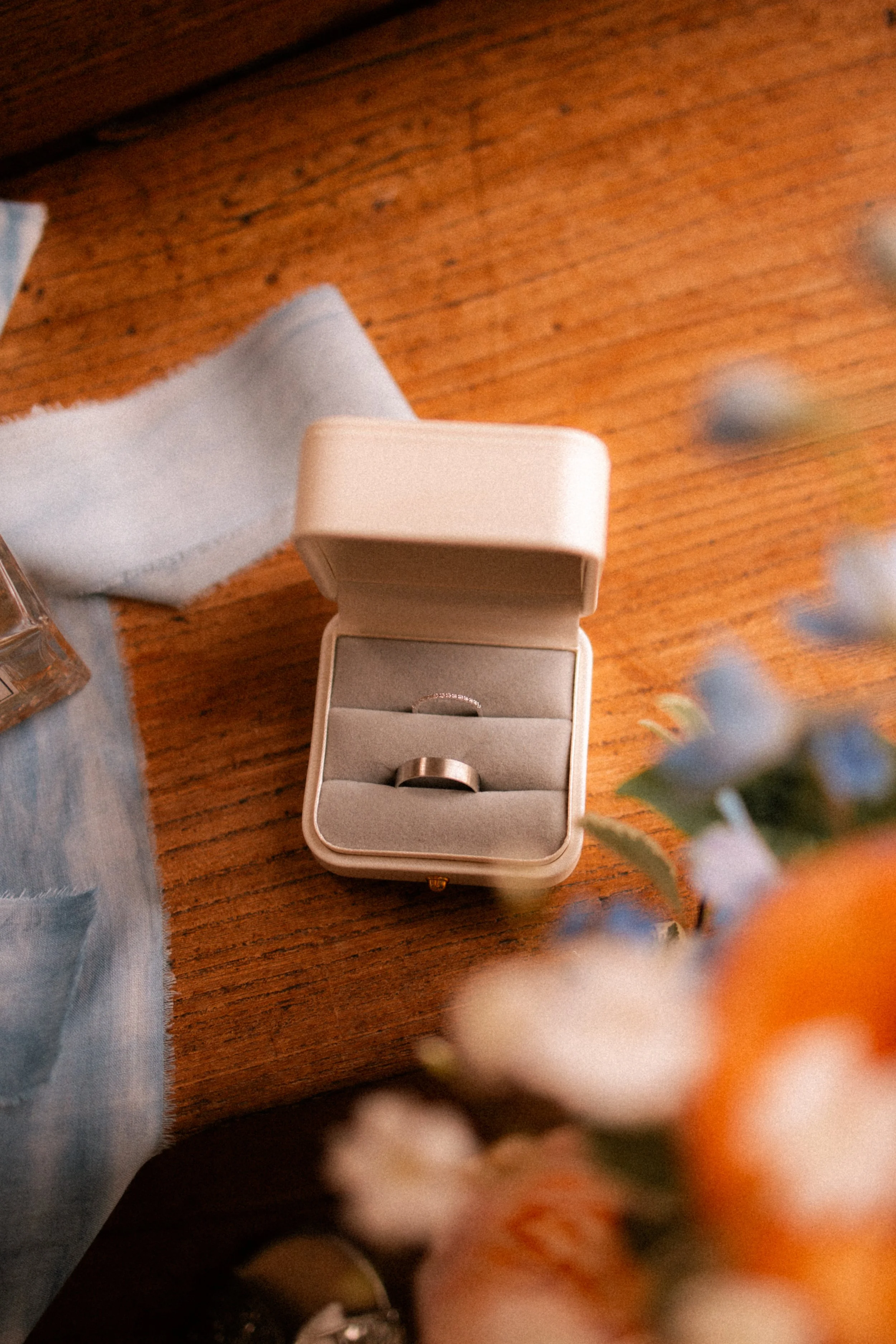 Une boîte à bijoux contenant une alliance en métal, posée sur une table en bois.
