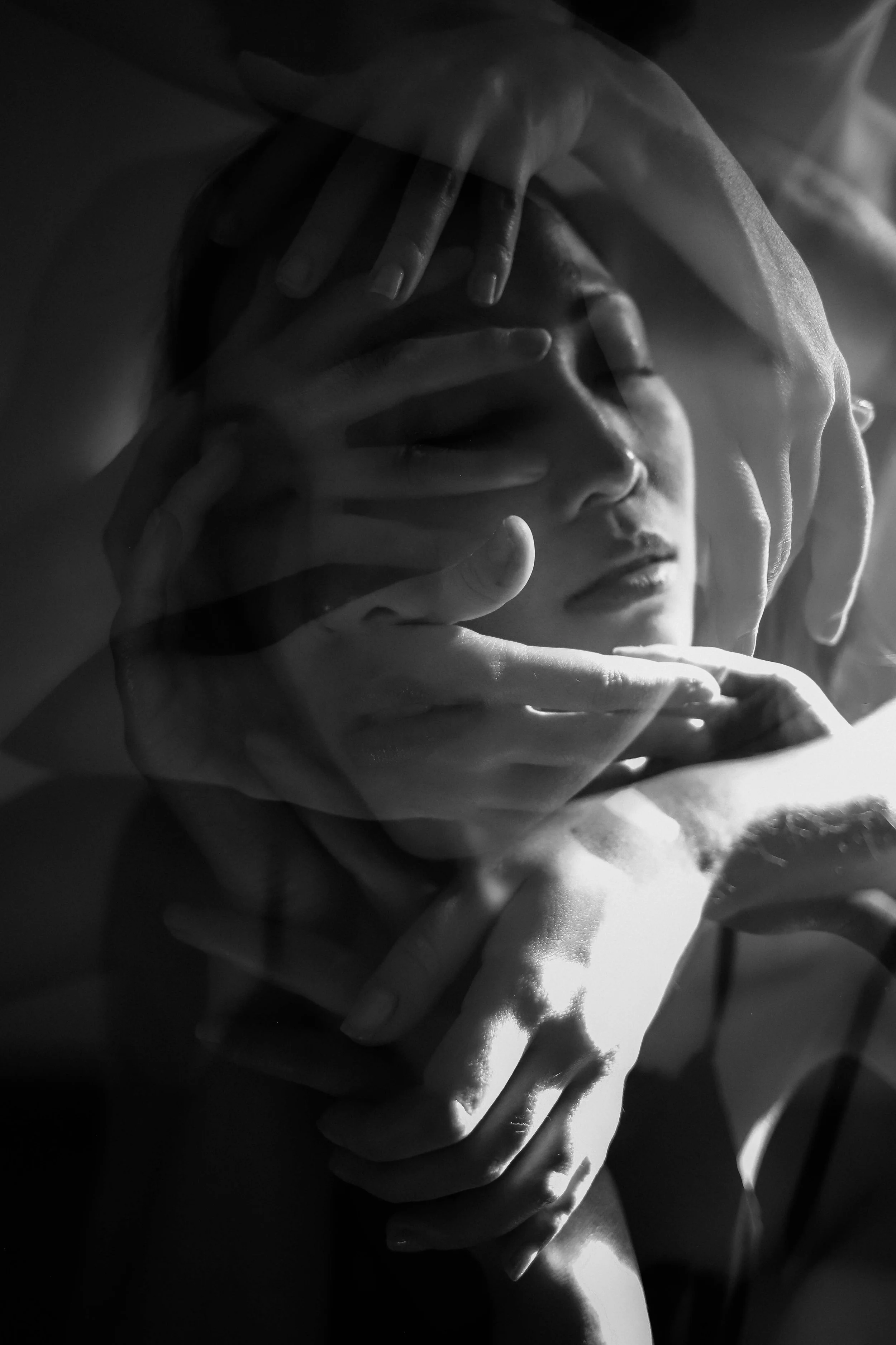 Une sculpture ou une installation artistique noire et blanche représentant plusieurs mains délicates entourant doucement un visage humain, évoquant la protection ou l'étreinte.