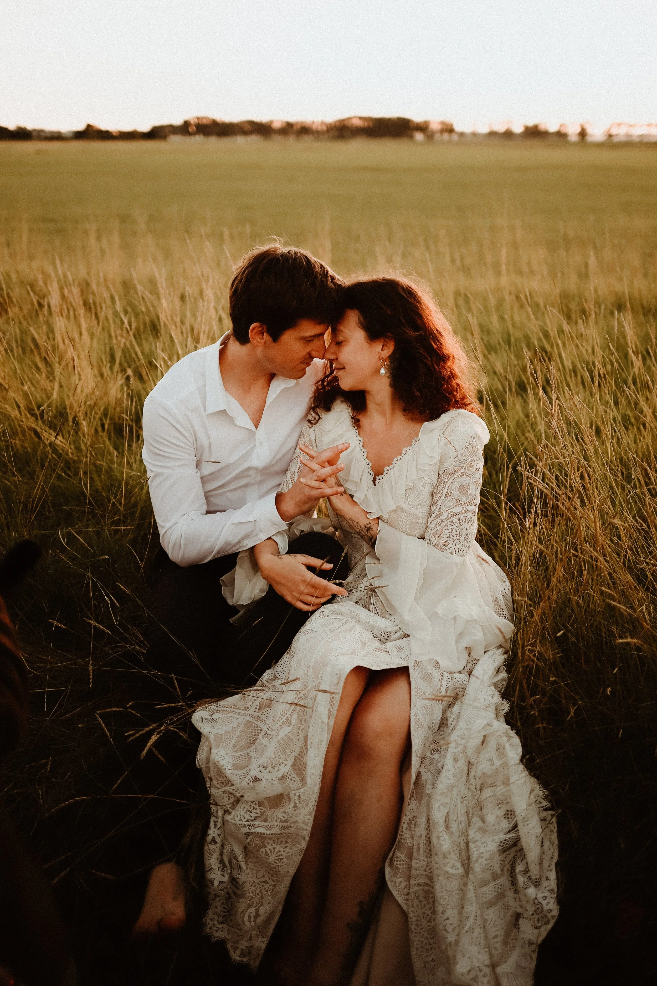 Un couple romantique s'embrasse dans un champ lors d'un coucher de soleil.