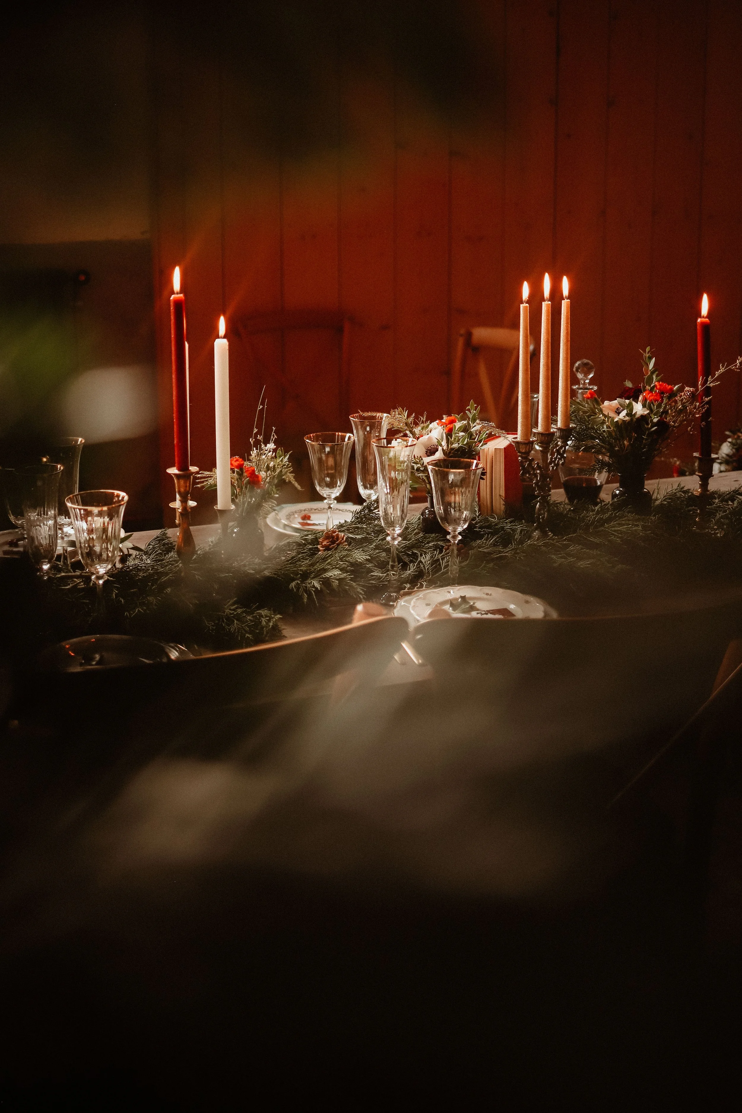 Table de dîner décorée avec des bougies, des fleurs et de la verdure, dans une ambiance chaleureuse et intime.