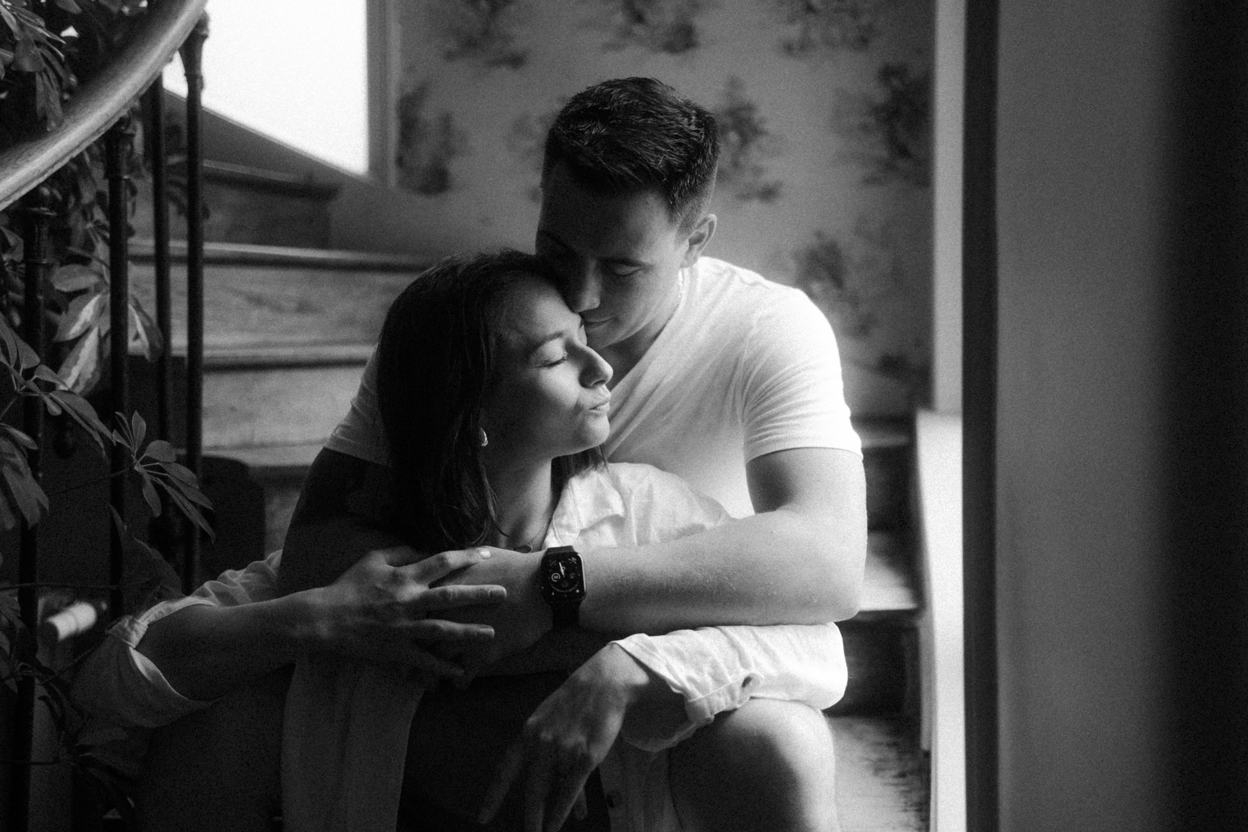 Un couple assis ensemble dans une maison, exprimant de l'affection et de tendresse, dans une ambiance intime.