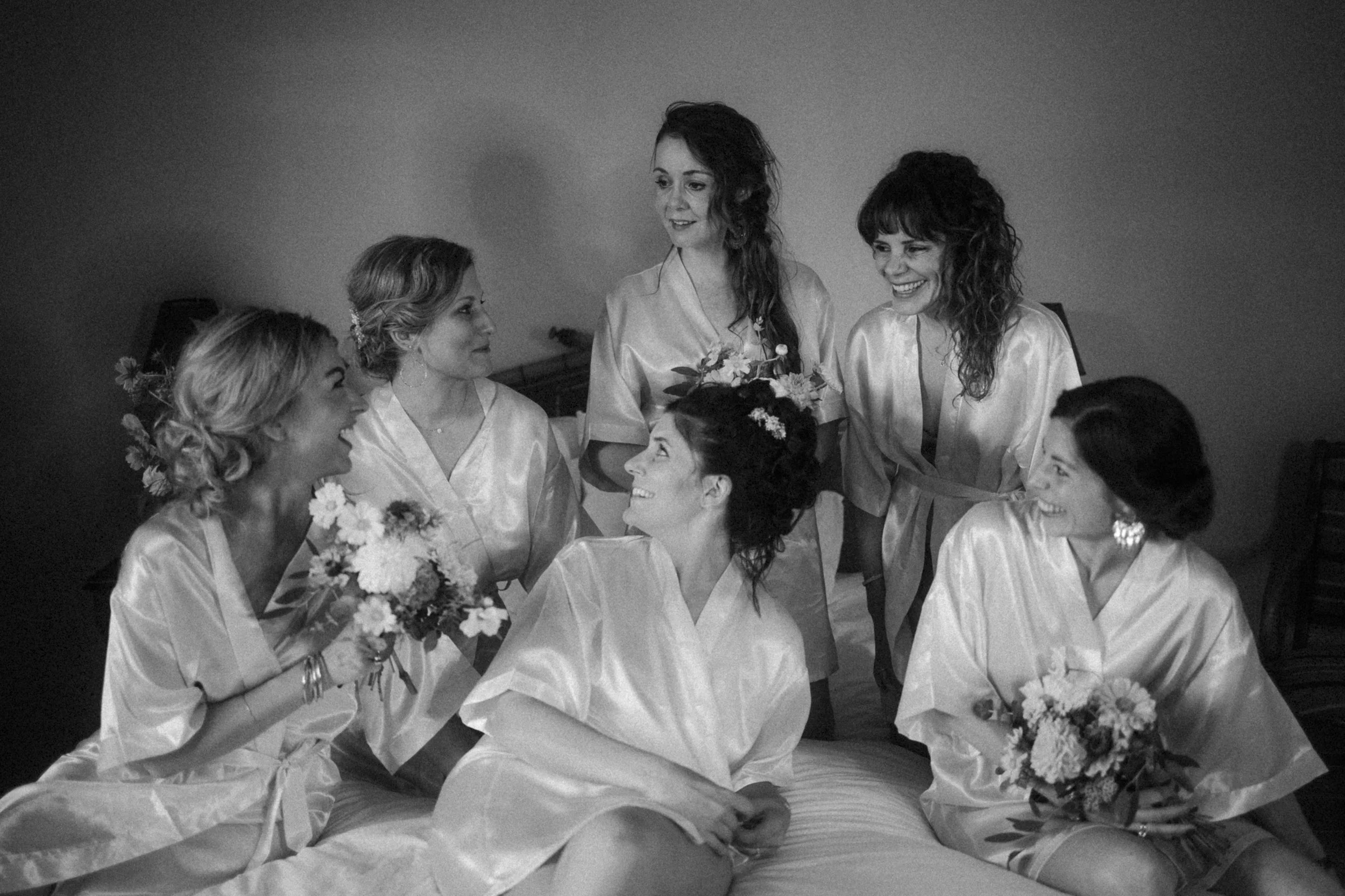 Groupe de femmes en robe de soie discutant et souriant, probablement lors d'une préparation de mariage.