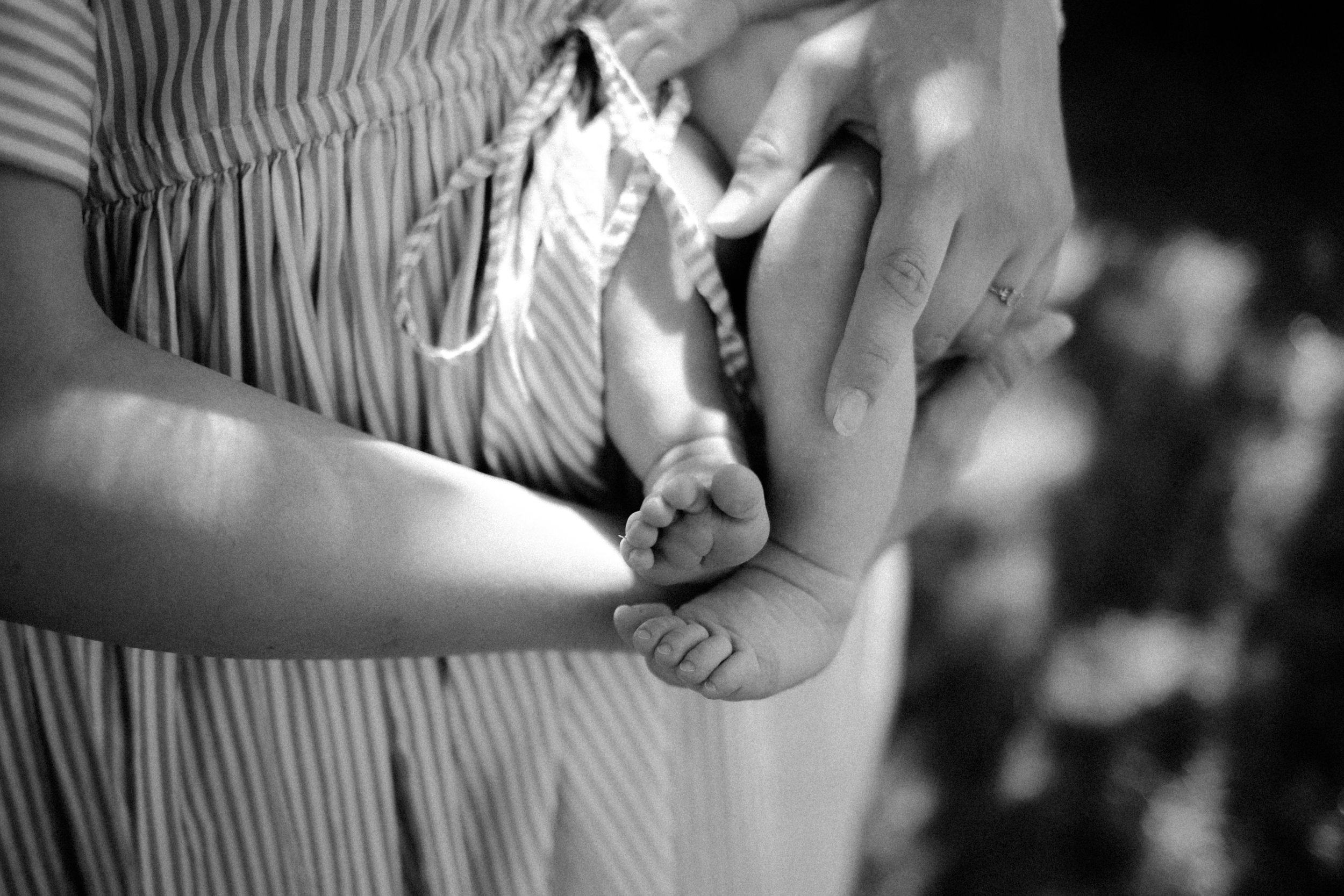 Une personne tient un bébé dans ses bras, en souciant affectueusement. Le bébé est petit et la personne montre une bague à son doigt.