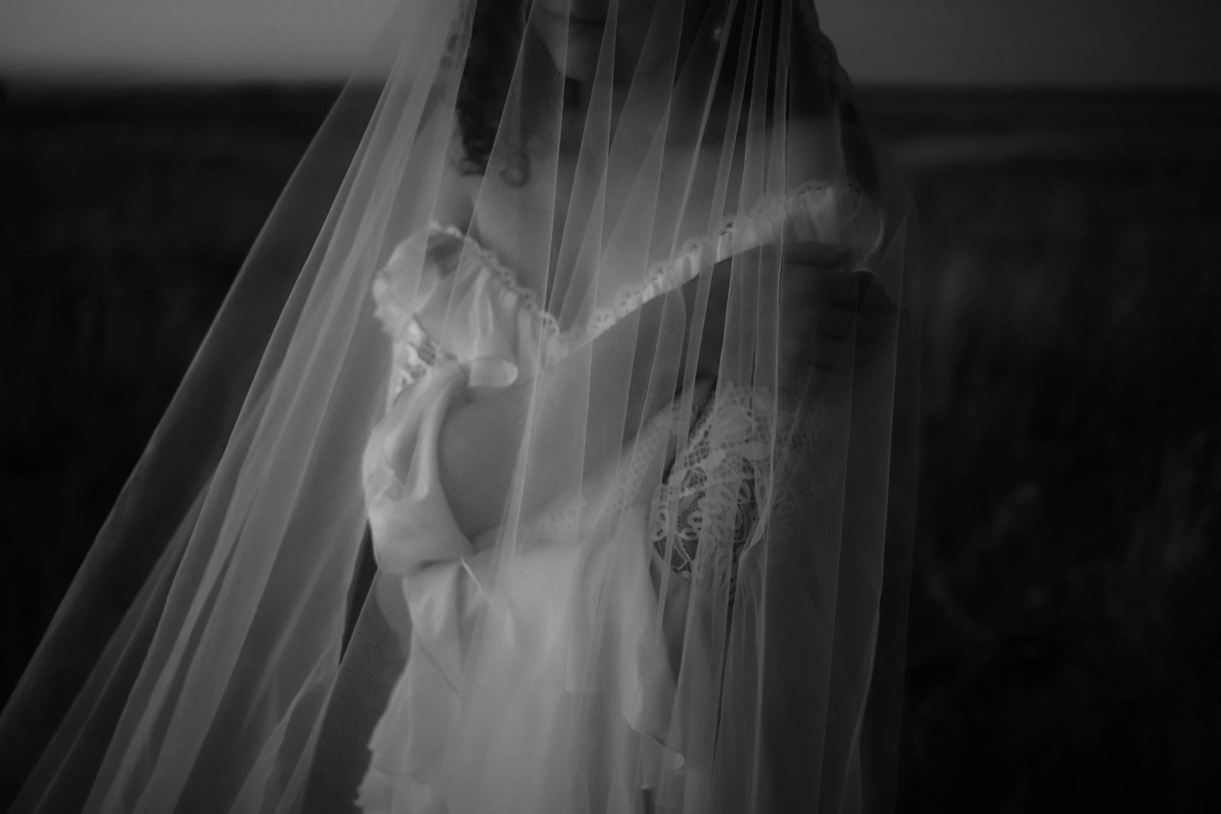 Une personne portant un voile blanc vintage, en tissu léger, dans une scène en noir et blanc.