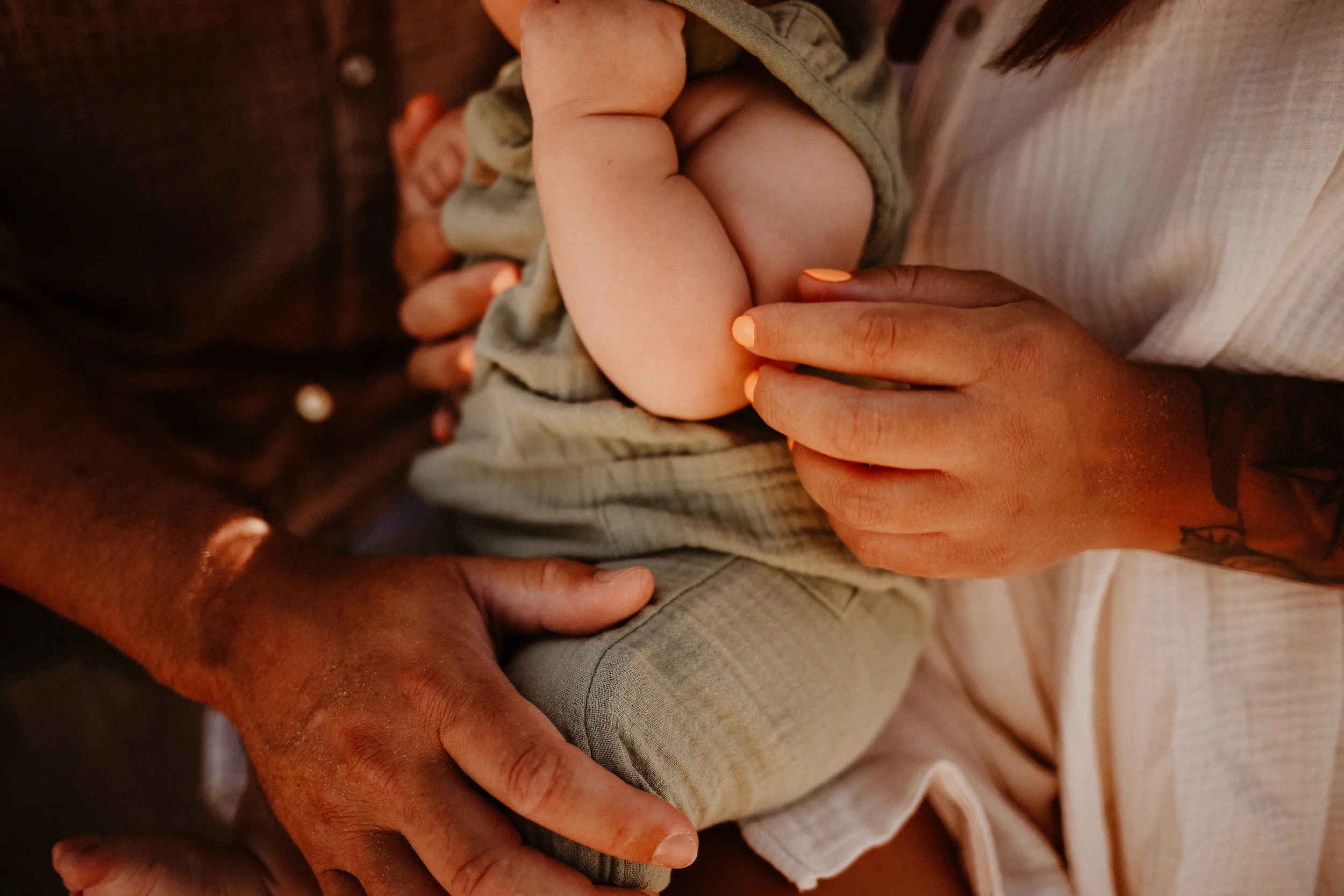 Deux mains, l'une d'un adulte avec une tache de souvenir, tenant doucement le bras ou la main d'un bébé, qui dort ou repose sur la personne, avec une ambiance chaleureuse et intime.
