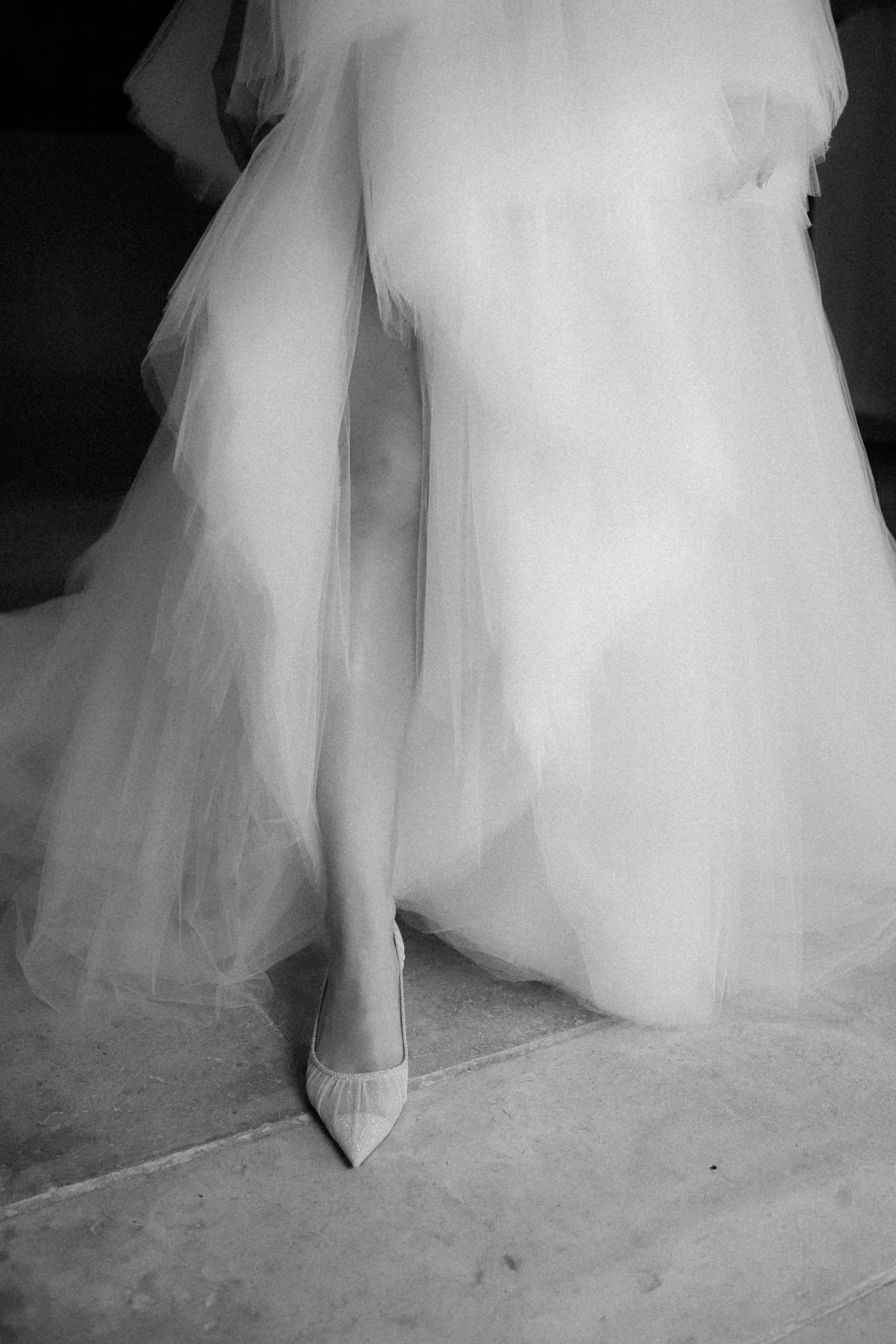 Pied d'une femme portant une chaussure à talon avec une robe de mariée en tulle