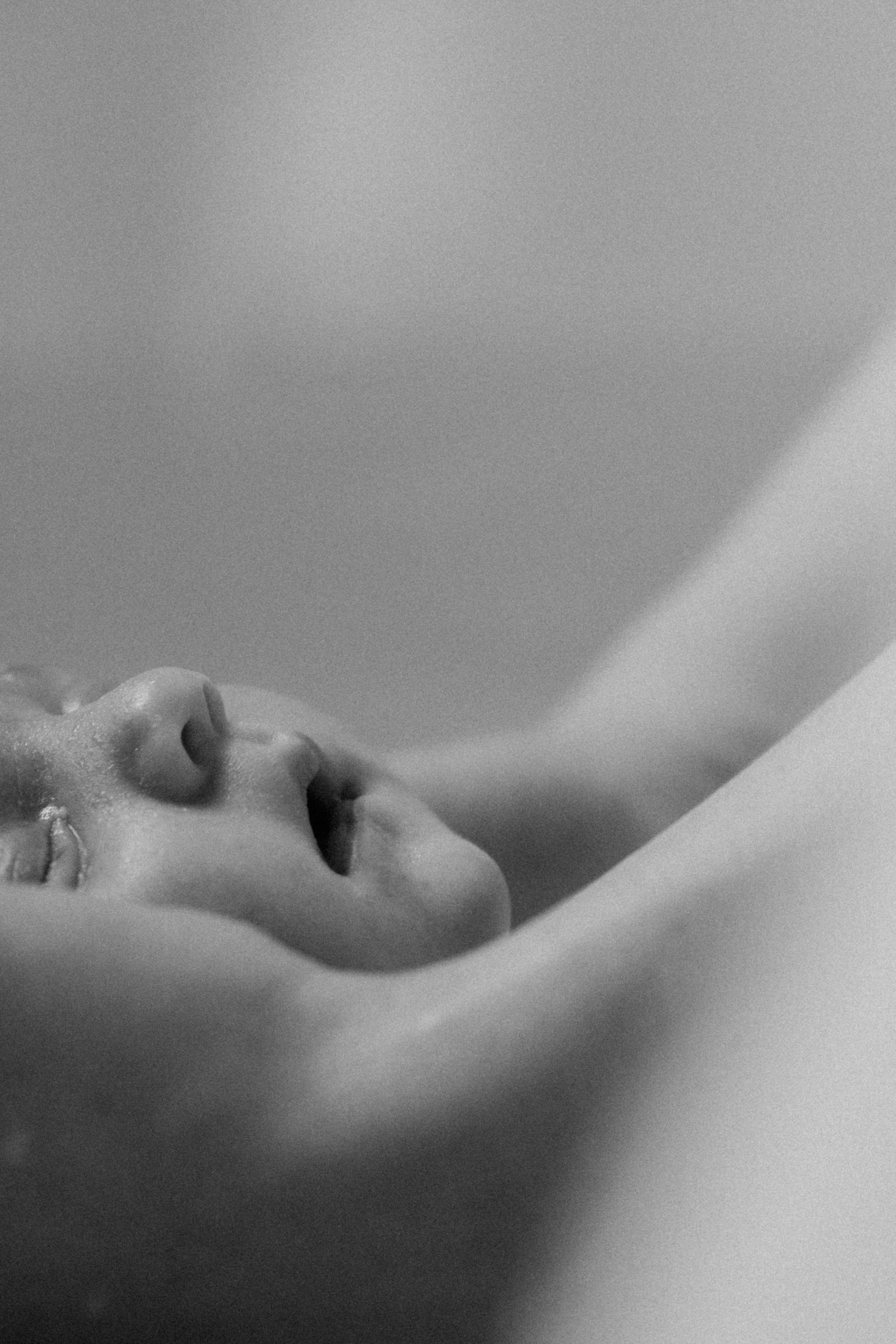 Un visage humain, probablement un bébé, vu de profil, avec la bouche entrouverte, en noir et blanc.