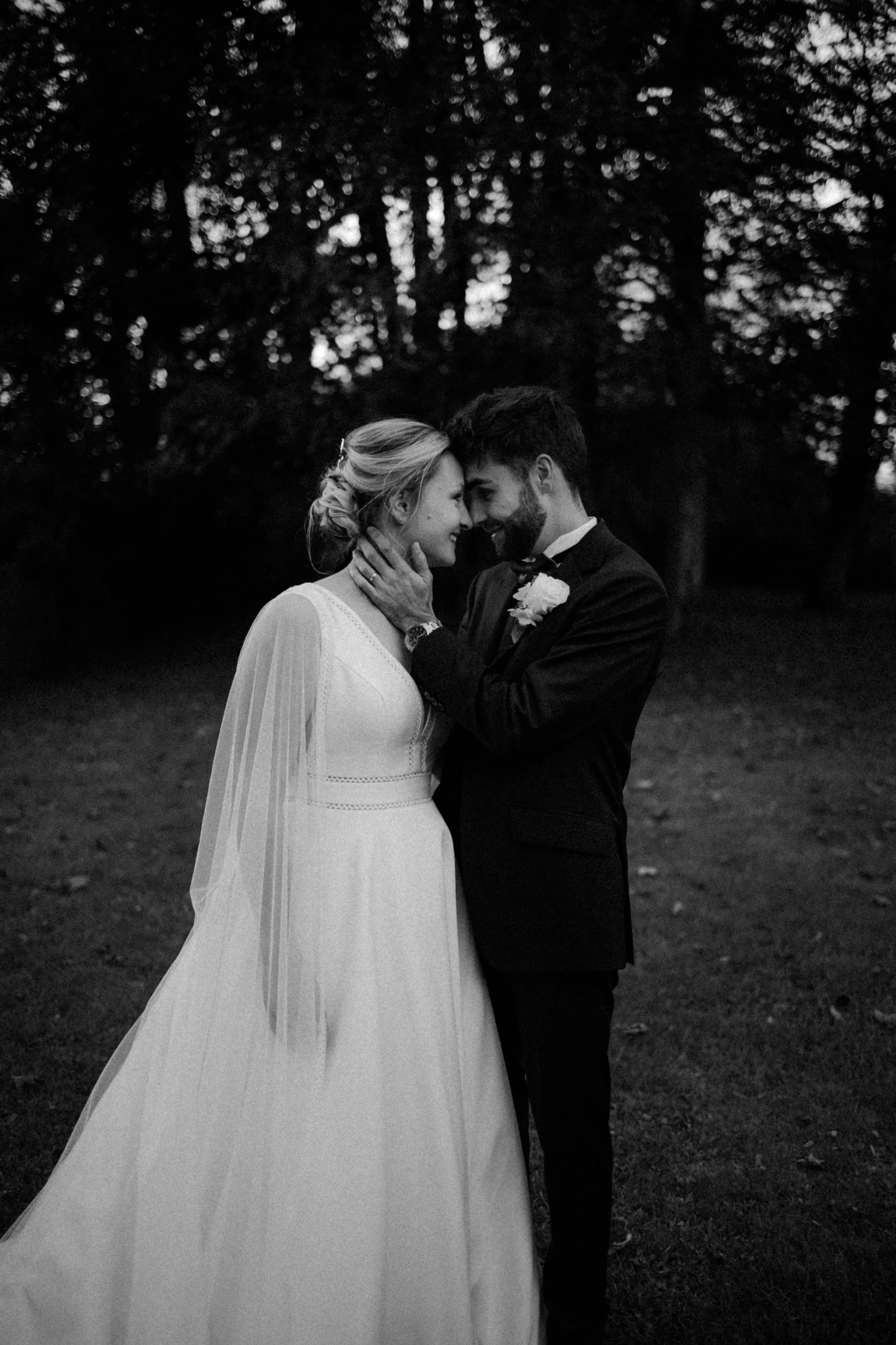Un couple de mariés se tient dans un environnement extérieur, s'enveloppant dans une atmosphère intime et romantique.