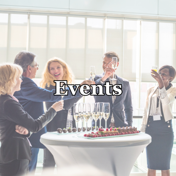 Group of five people at a celebration toast with champagne in a bright, modern venue, with a table of champagne glasses and snacks, labeled 'Events'.