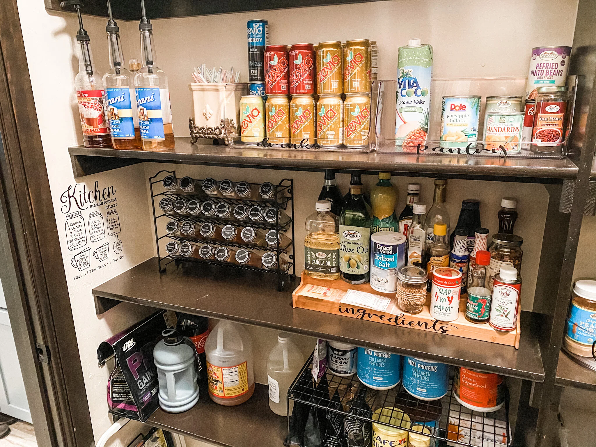AfterThe lower shelf houses the drink mixes utilized daily. I arranged this area so the user can bring their cup into the pantry, place it on the shelf, fill it with the mixes needed, and be on their way. Before, each container (4) was carried out t…