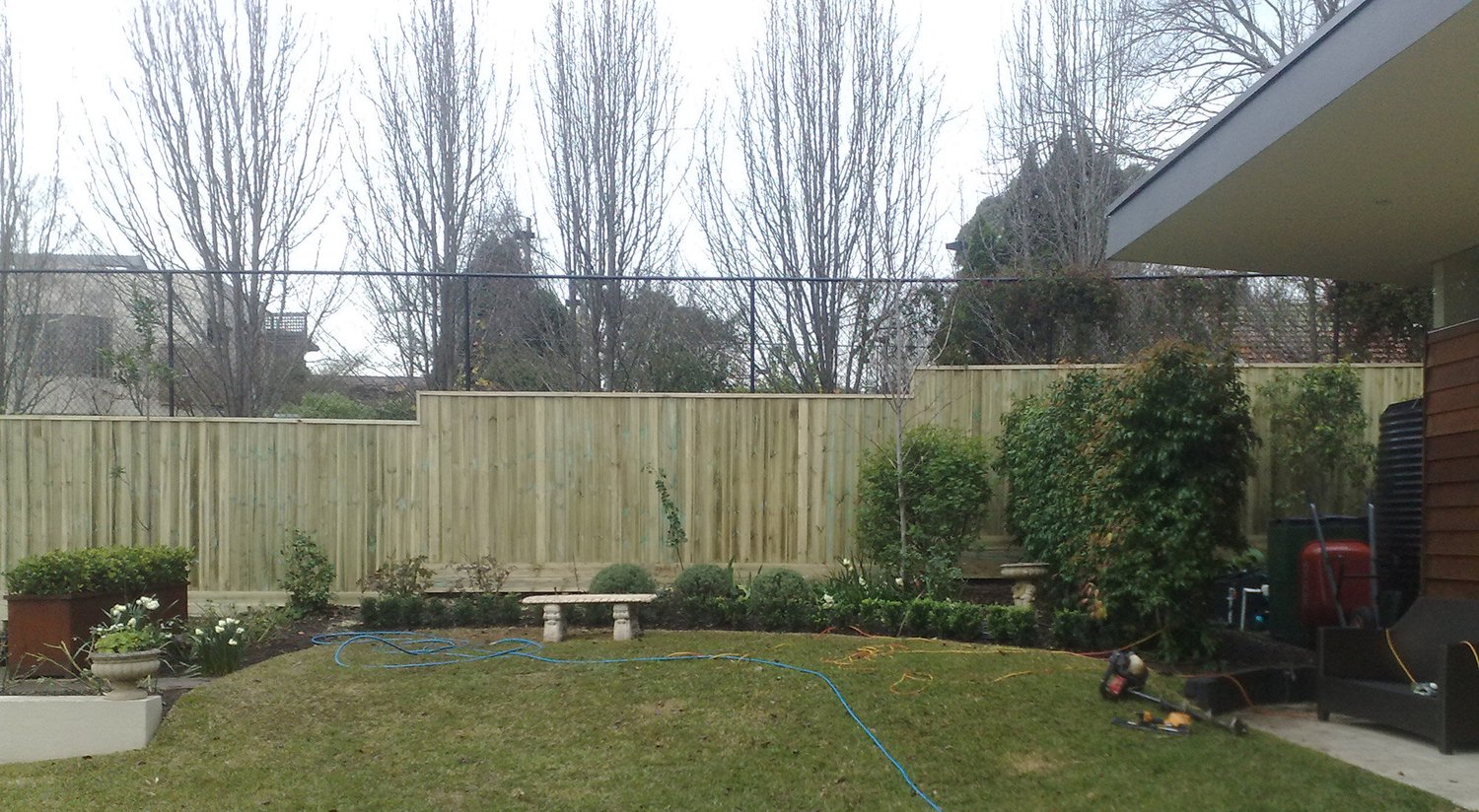 Stepped timber paling fence with garden beds