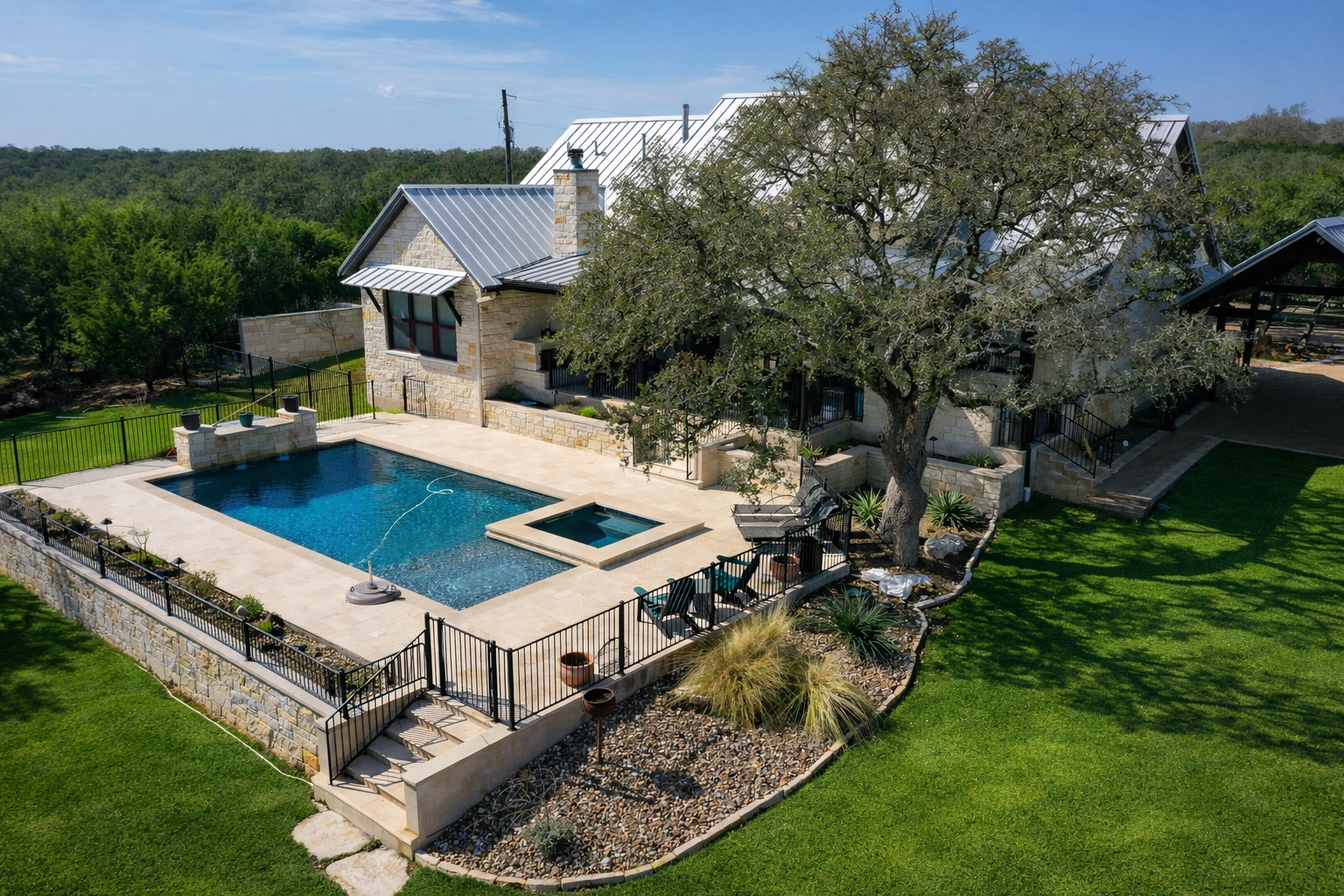A backyard with a swimming pool and hot tub, enclosed by a black fence, in front of a stone house with a metal roof. There are lounge chairs and landscaping, with trees and greenery in the background. A sign indicates a 5-star rated pool.