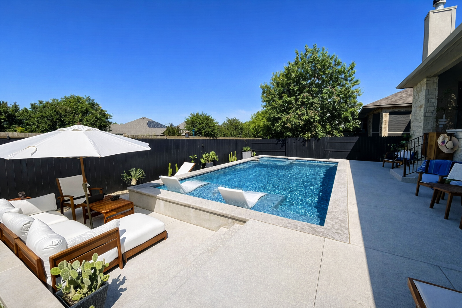 A backyard with a rectangular swimming pool surrounded by a concrete deck, two lounge chairs by the pool, a wooden table with four chairs, and a large sign reading '5 Star Rated Pool' with five stars at the top.