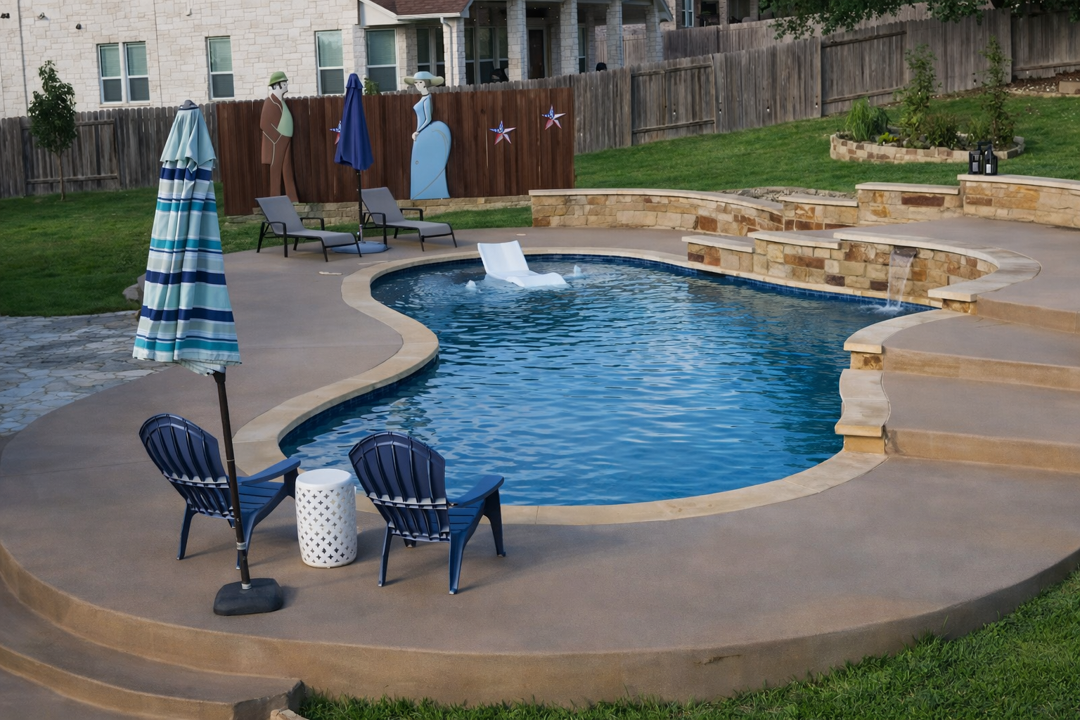 Residential backyard with a swimming pool featuring waterfall edges, a white pool slide, and a large blue banner reading "5 Star Rated Pool" with a five-star rating above it, surrounded by outdoor furniture including chairs and a side table.