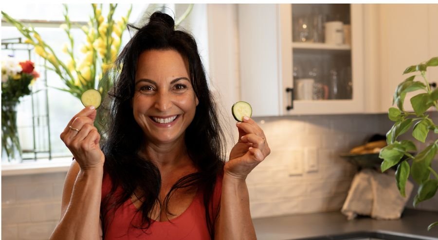 Dr. Bianca Beldini holding cucumber slices in her kitchen