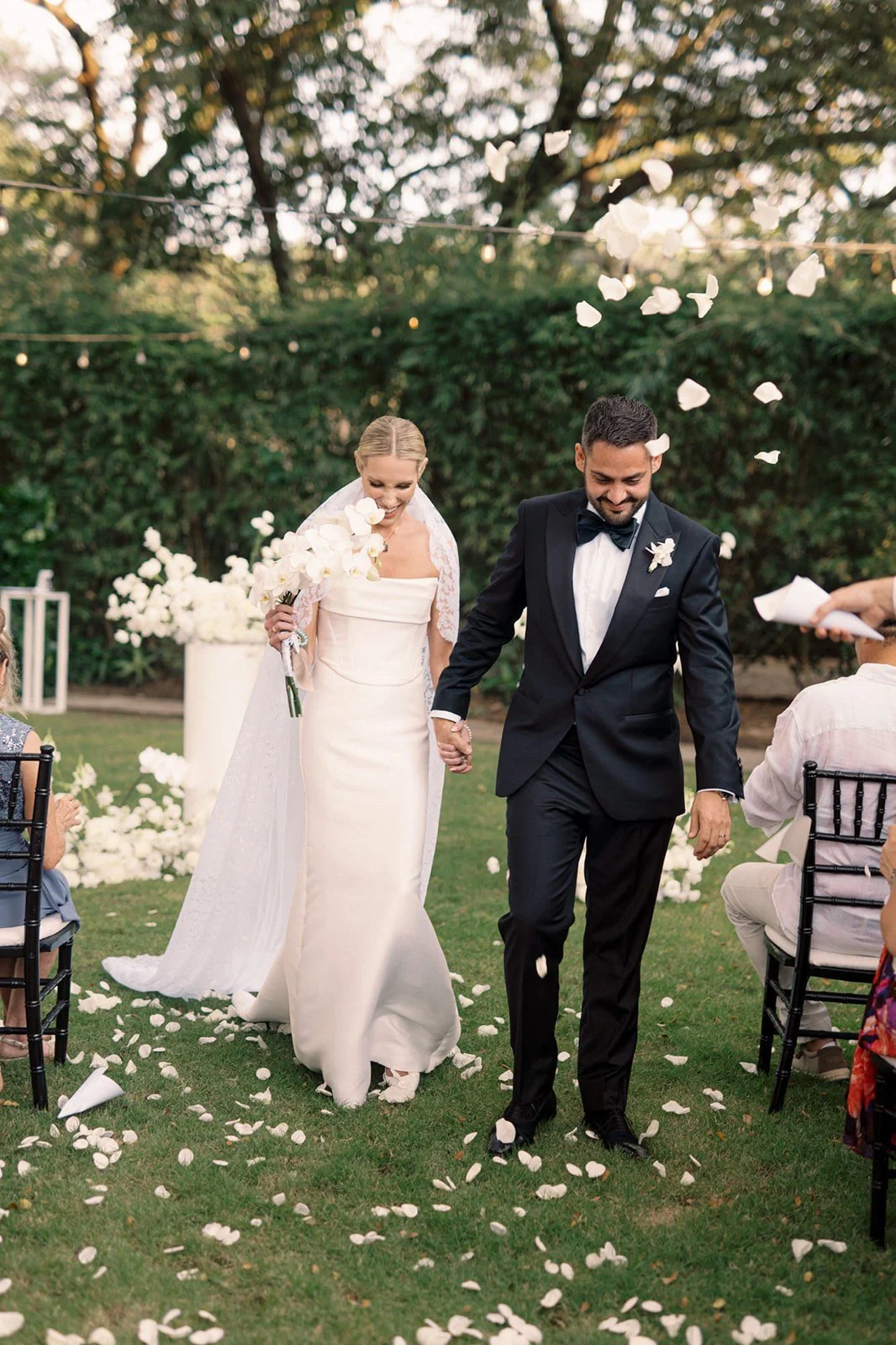 Newlywed couple surrounded by elegant black and white wedding flowers at El Mangroove.