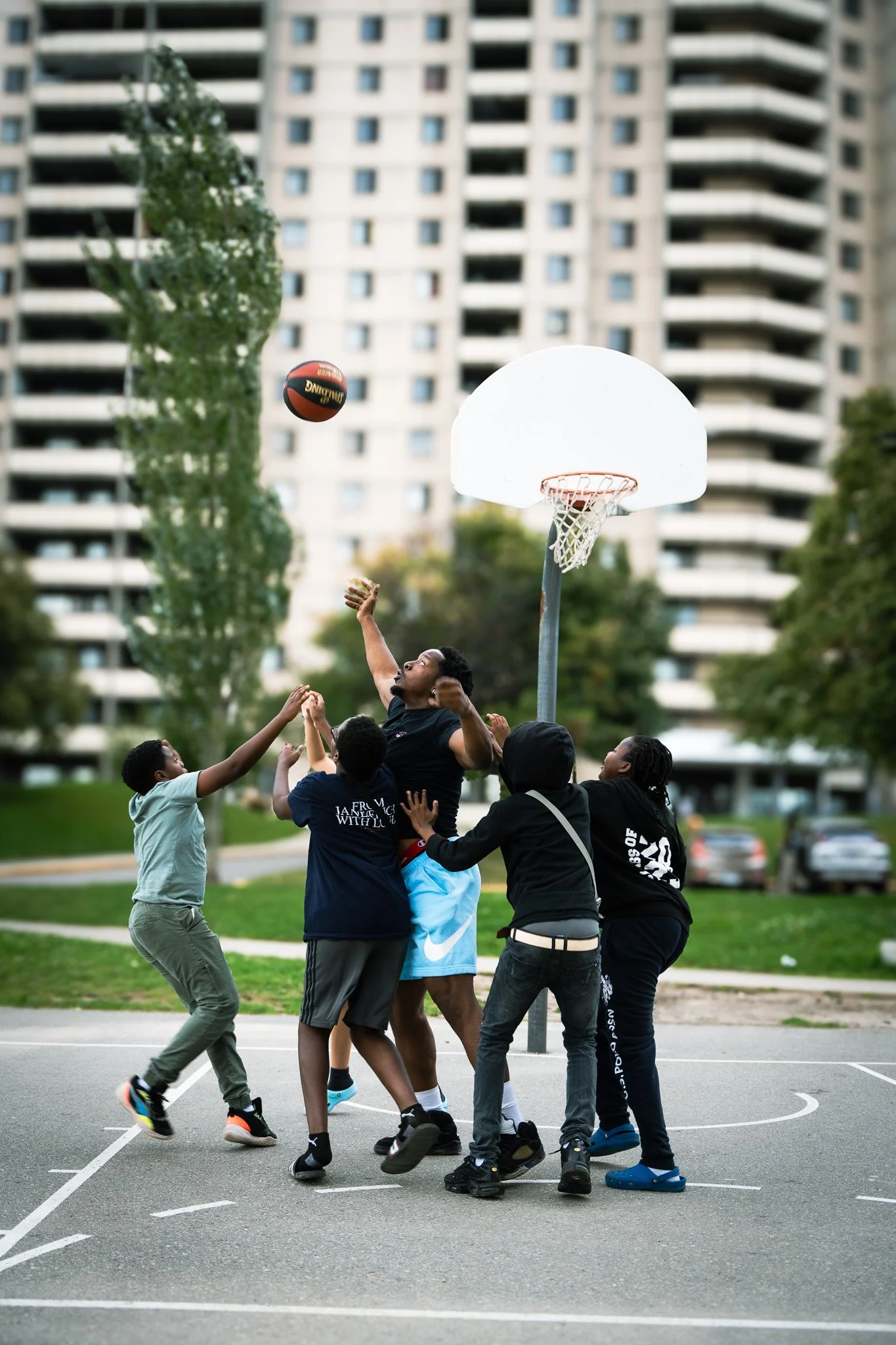 Group of boys playing basketball on an outdoor court in Jane-Finch