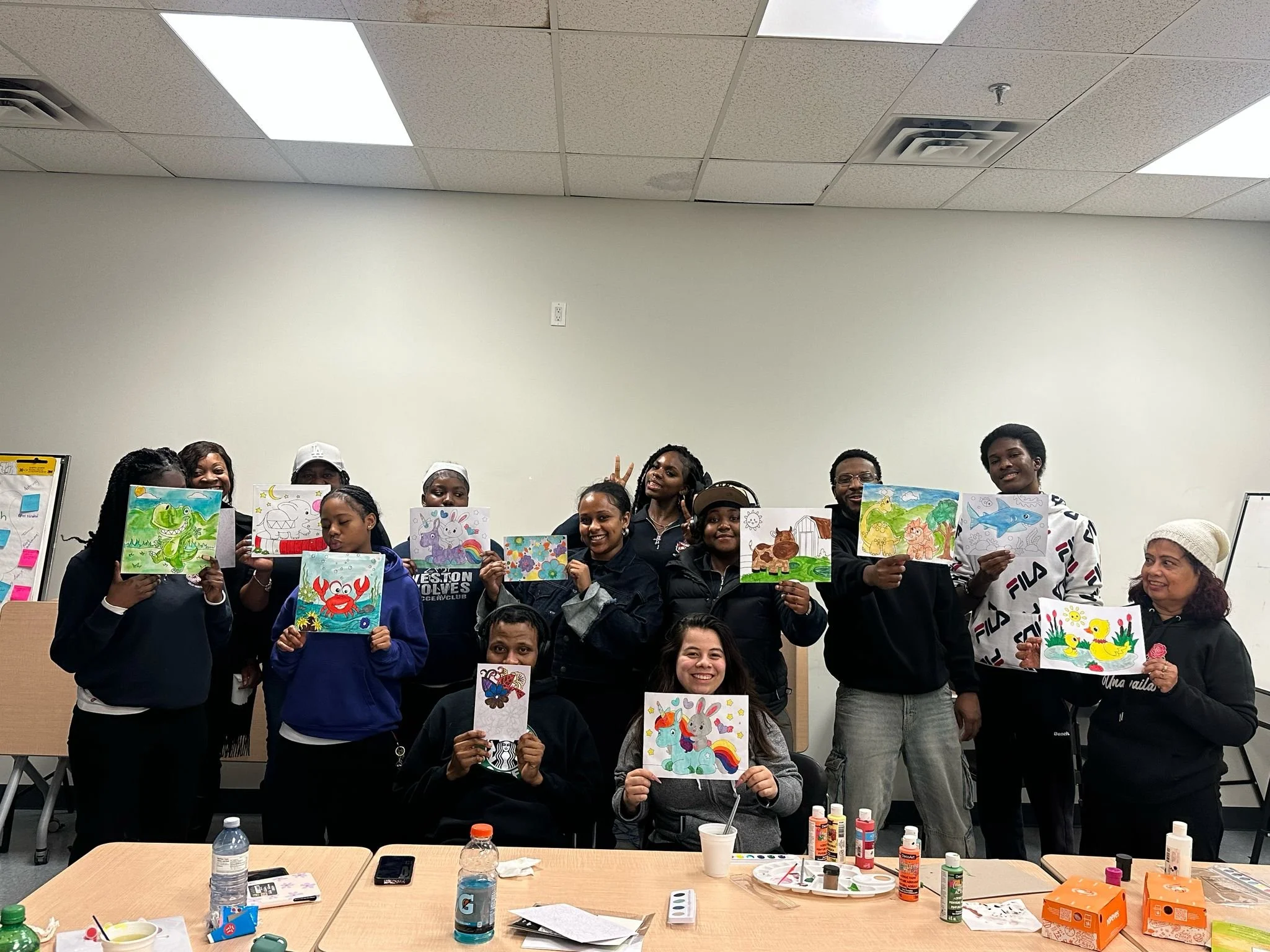 Group of participants displaying their artwork from a youth program in Jane-Finch