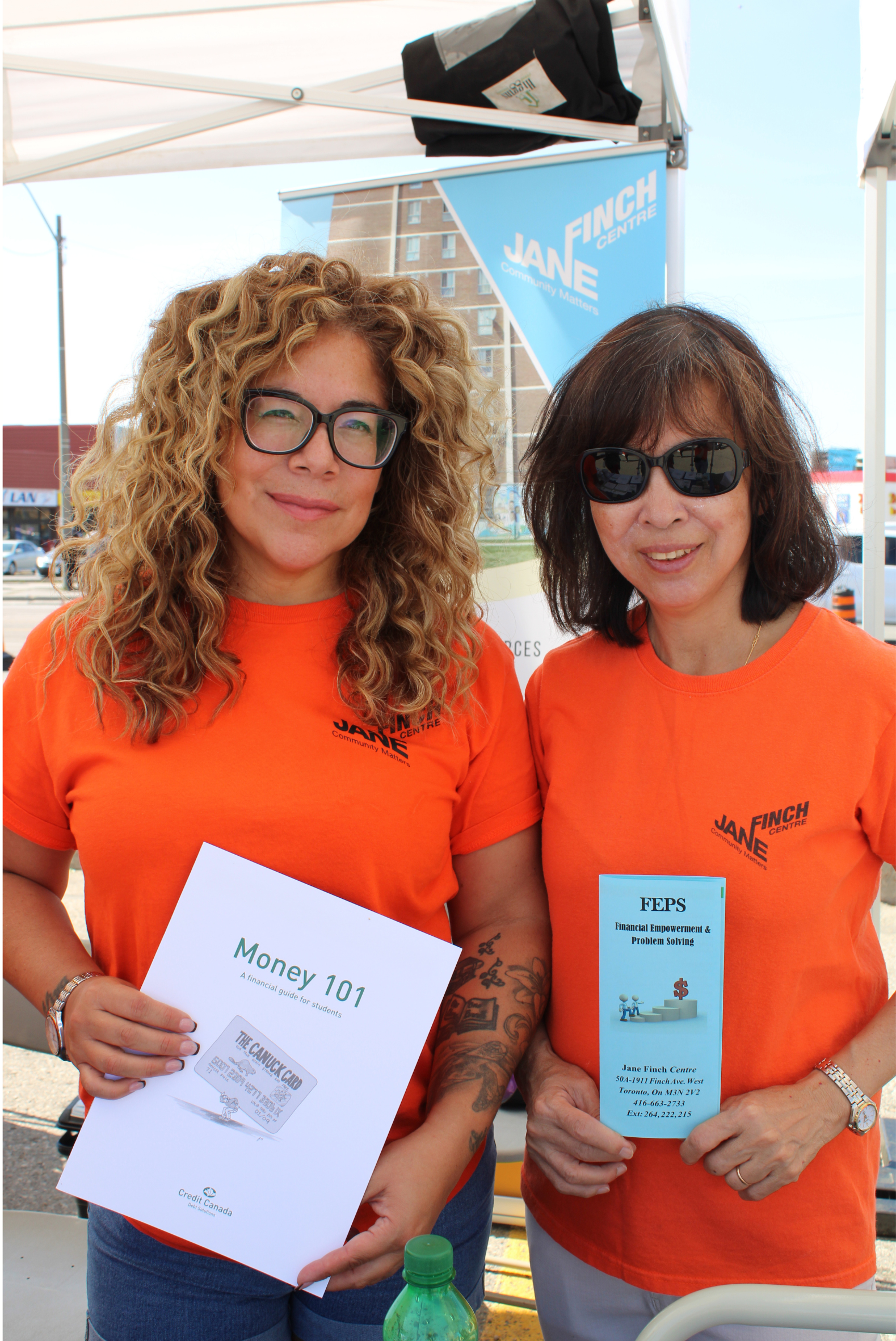 Two financial services staff smiling and holding financial information pamphlets