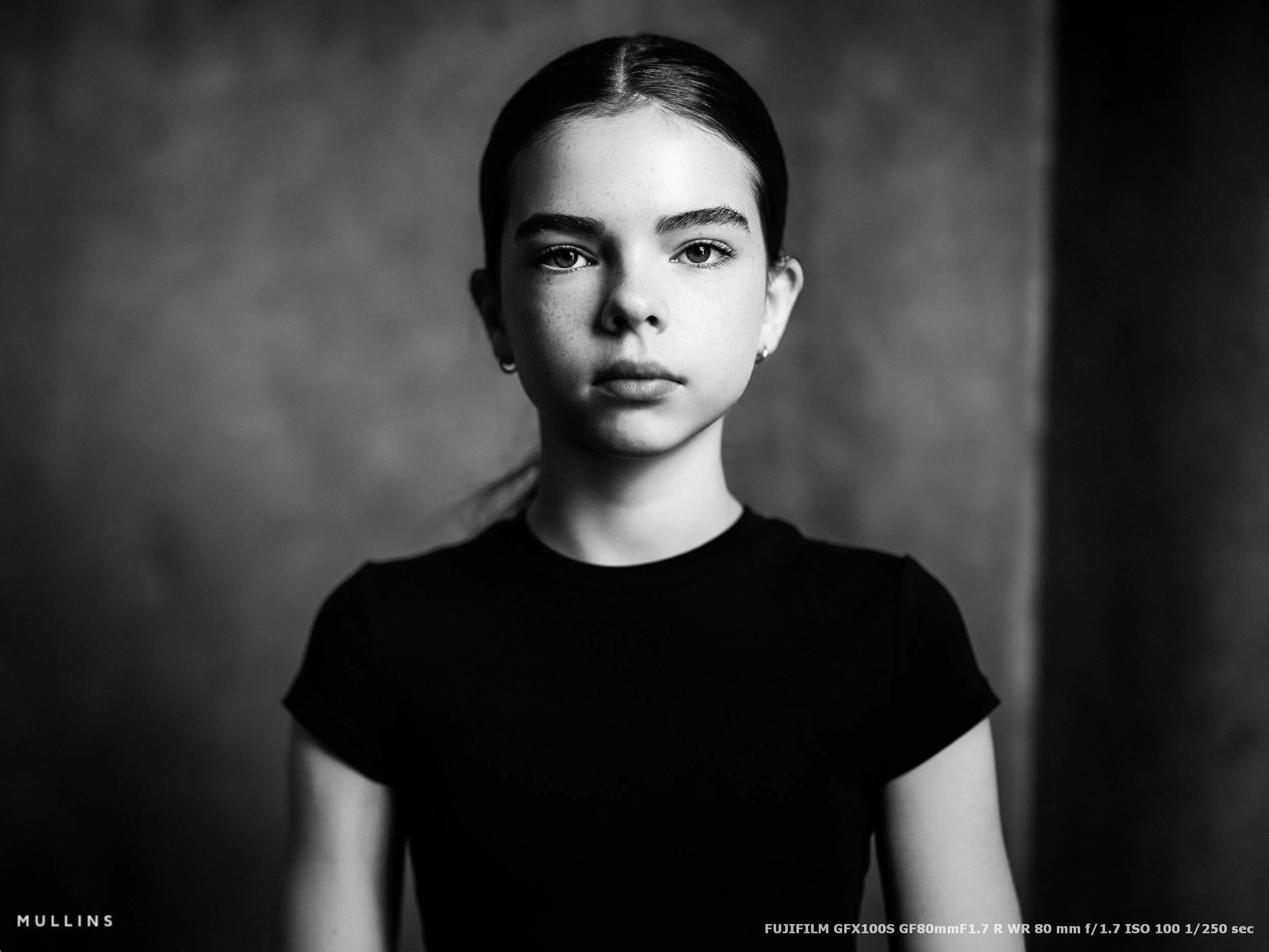 A black and white portrait of a young girl in a studio taken with a Fuji GFX system.