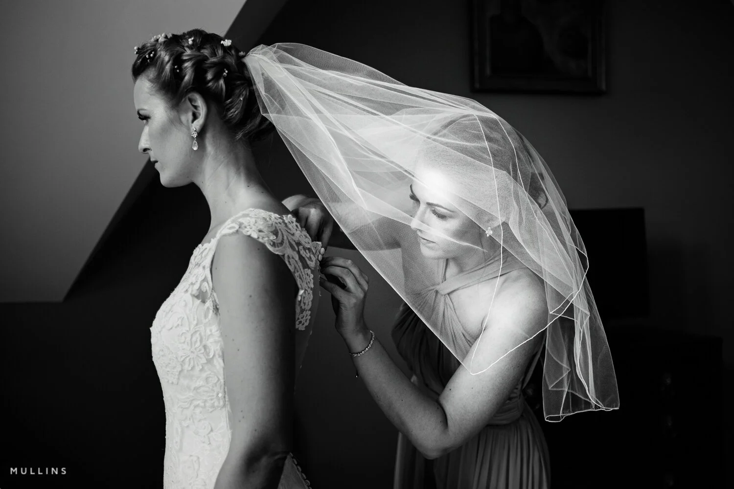 Bridesmaid helps a bride into her dress
