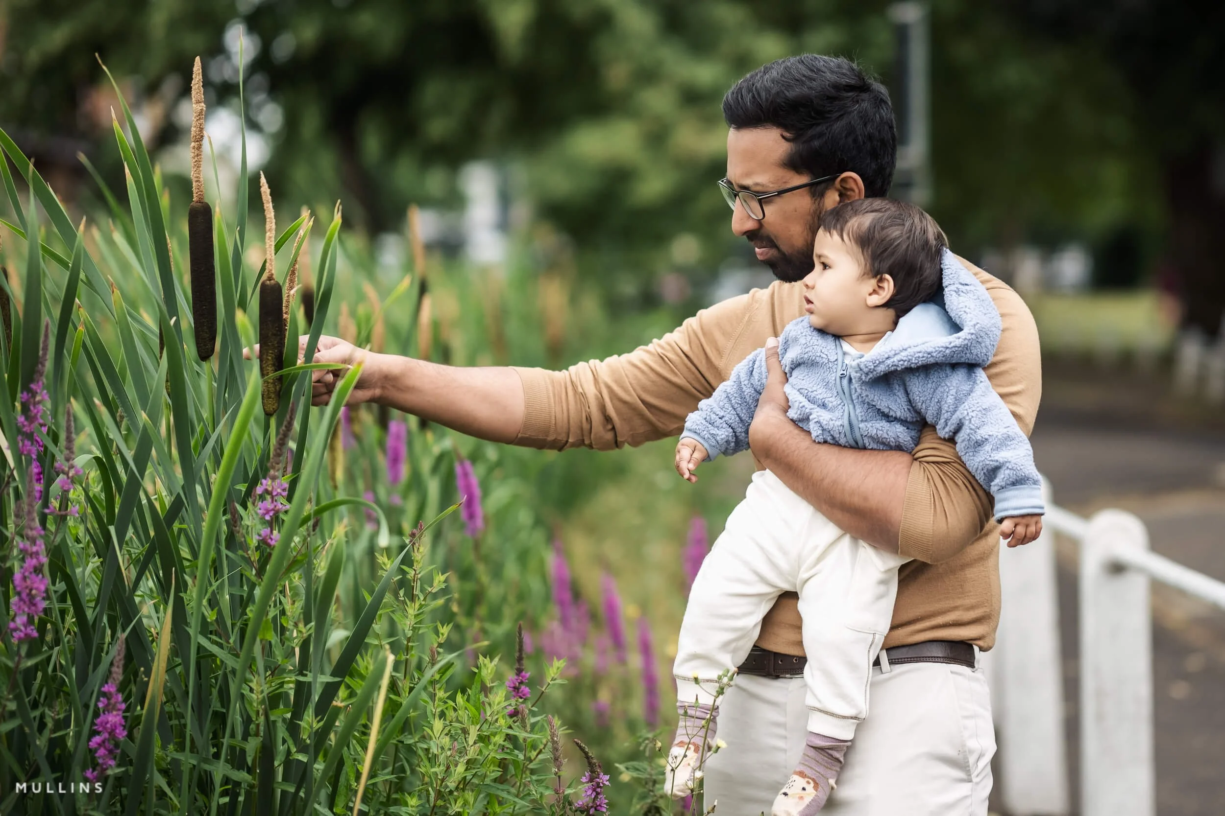 A father shows his baby son some flowers