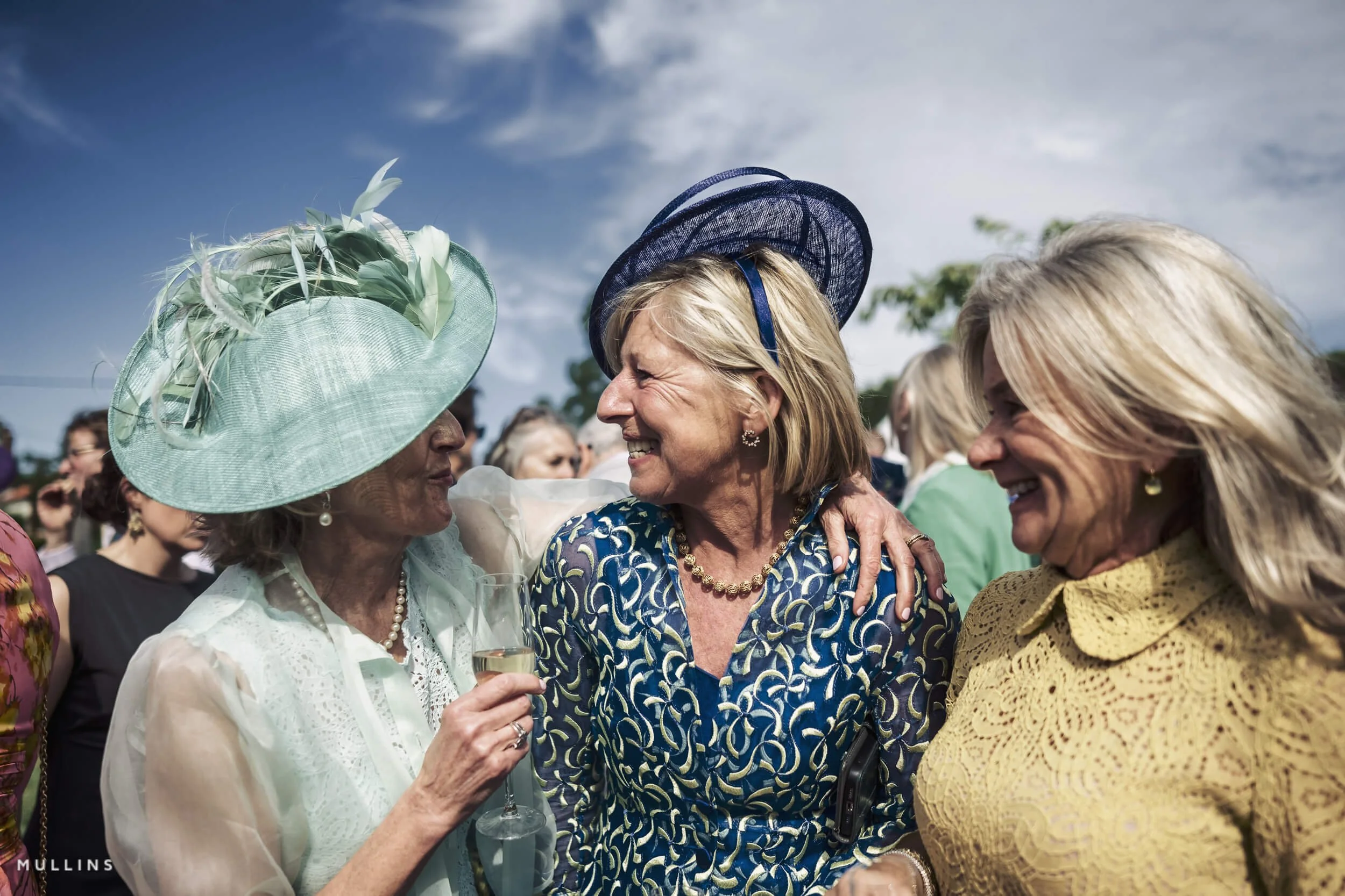 Three ladies laughing and smiling at a wedding