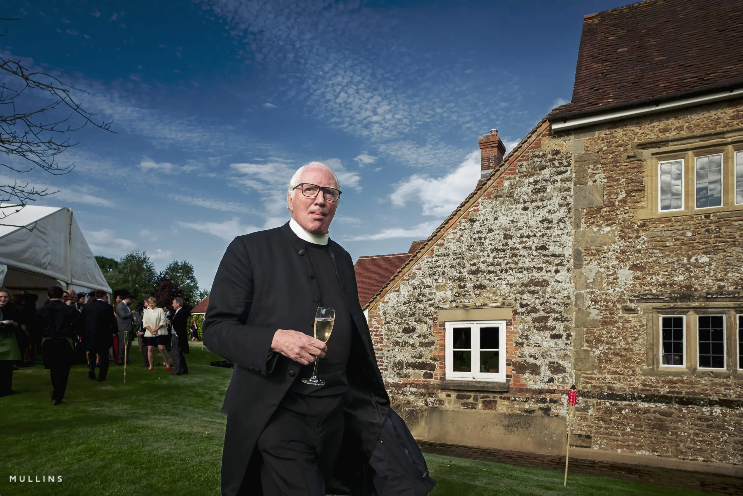 A vicar holding a glass of wine