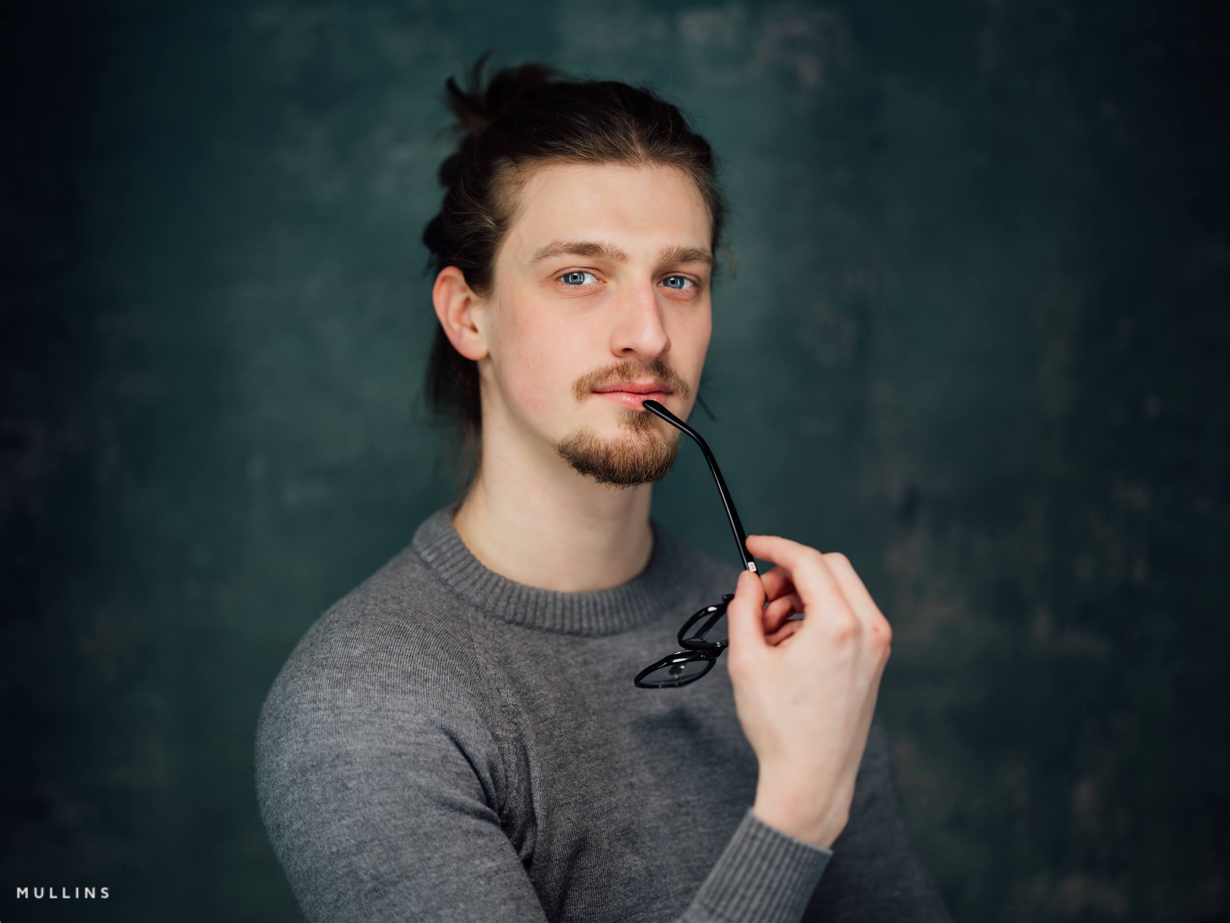 Characterful portrait of actor Tom Joy holding glasses during a relaxed headshot session in Malmesbury studio.