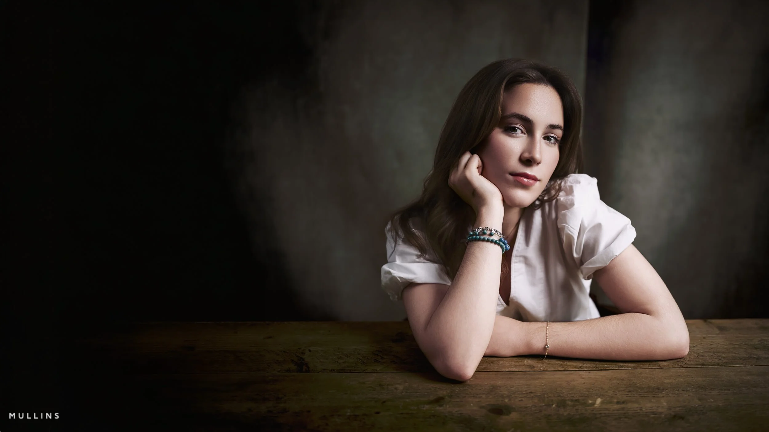 young actress sat behind a wooden desk