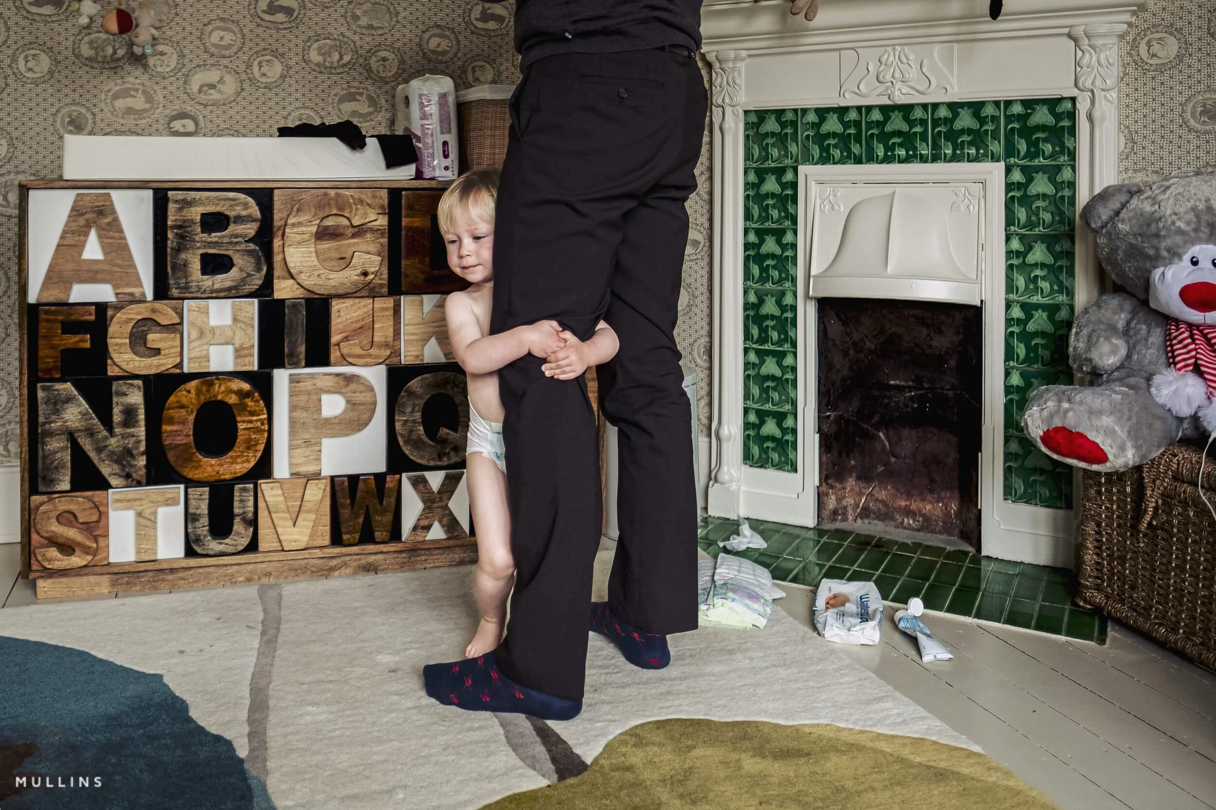 Quiet documentary family photograph showing a parent and child in an ordinary moment at home.