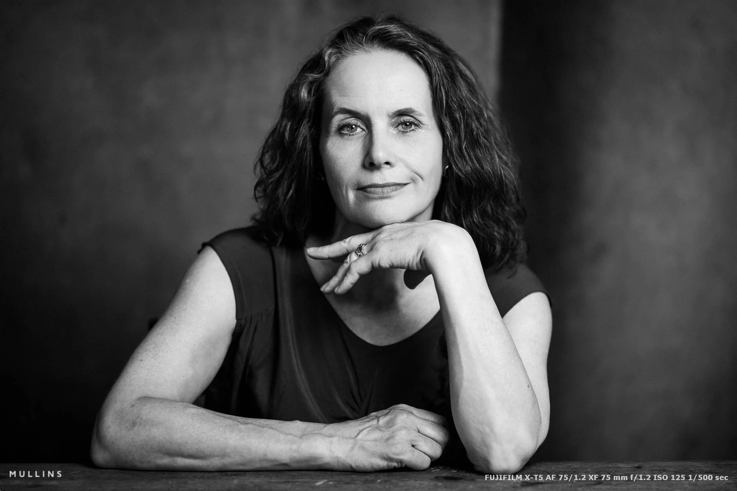 Close black-and-white actor portrait at a table with her chin resting on one hand