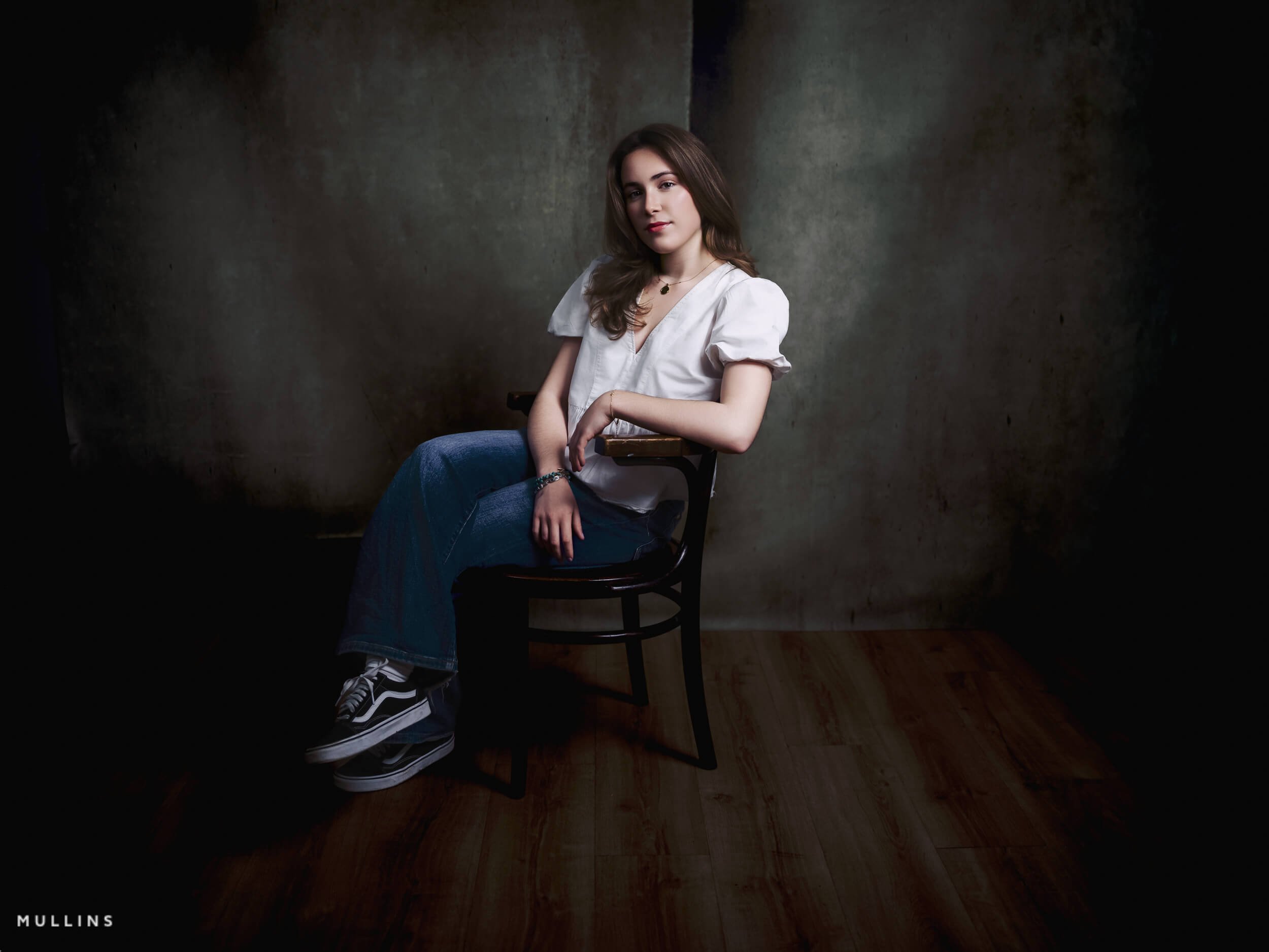 Seated actor portfolio photo of a young actress in a white blouse and jeans on a wooden chair in the Malmesbury studio.