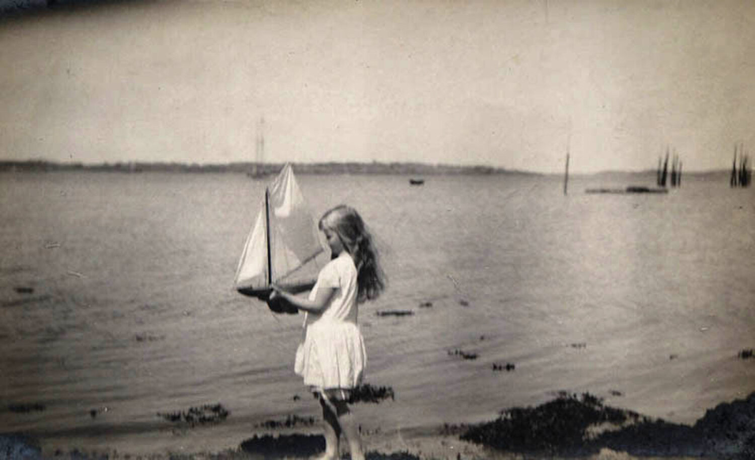 Anna Roosevelt joue avec un voilier jouet au bord de l'océan, à l'île de Campobello, au Nouveau-Brunswick (Canada).