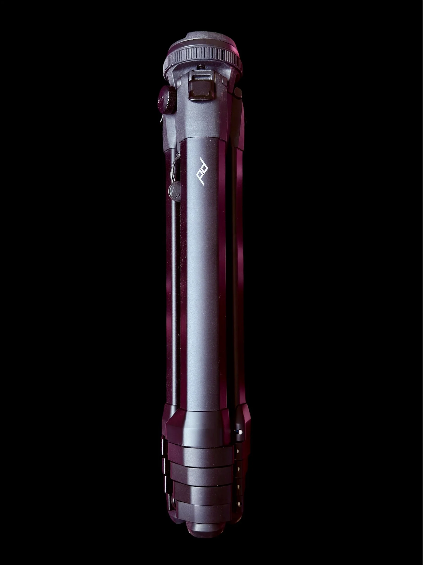 A black and gray flashlight with a textured grip and a button on the side, set against a black background.