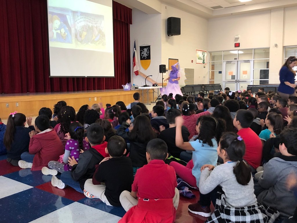 To read to a large group, The Book Fairy uses a digital document camera connected to a projector to show the images on a screen.