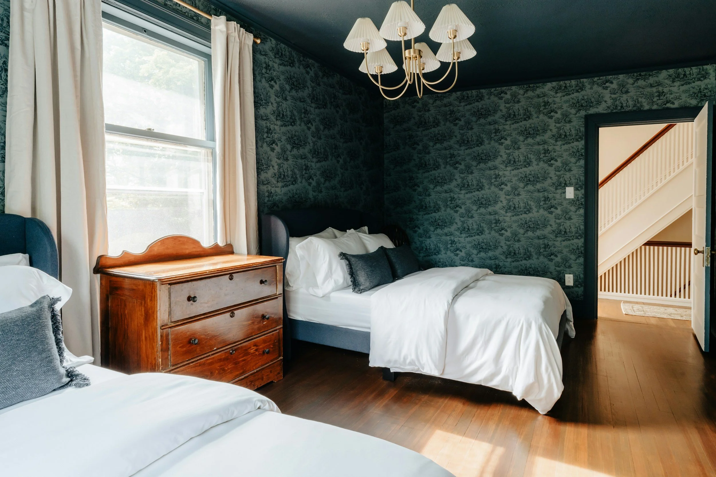 blue patterned wallpaper in bedroom with brass light fixture