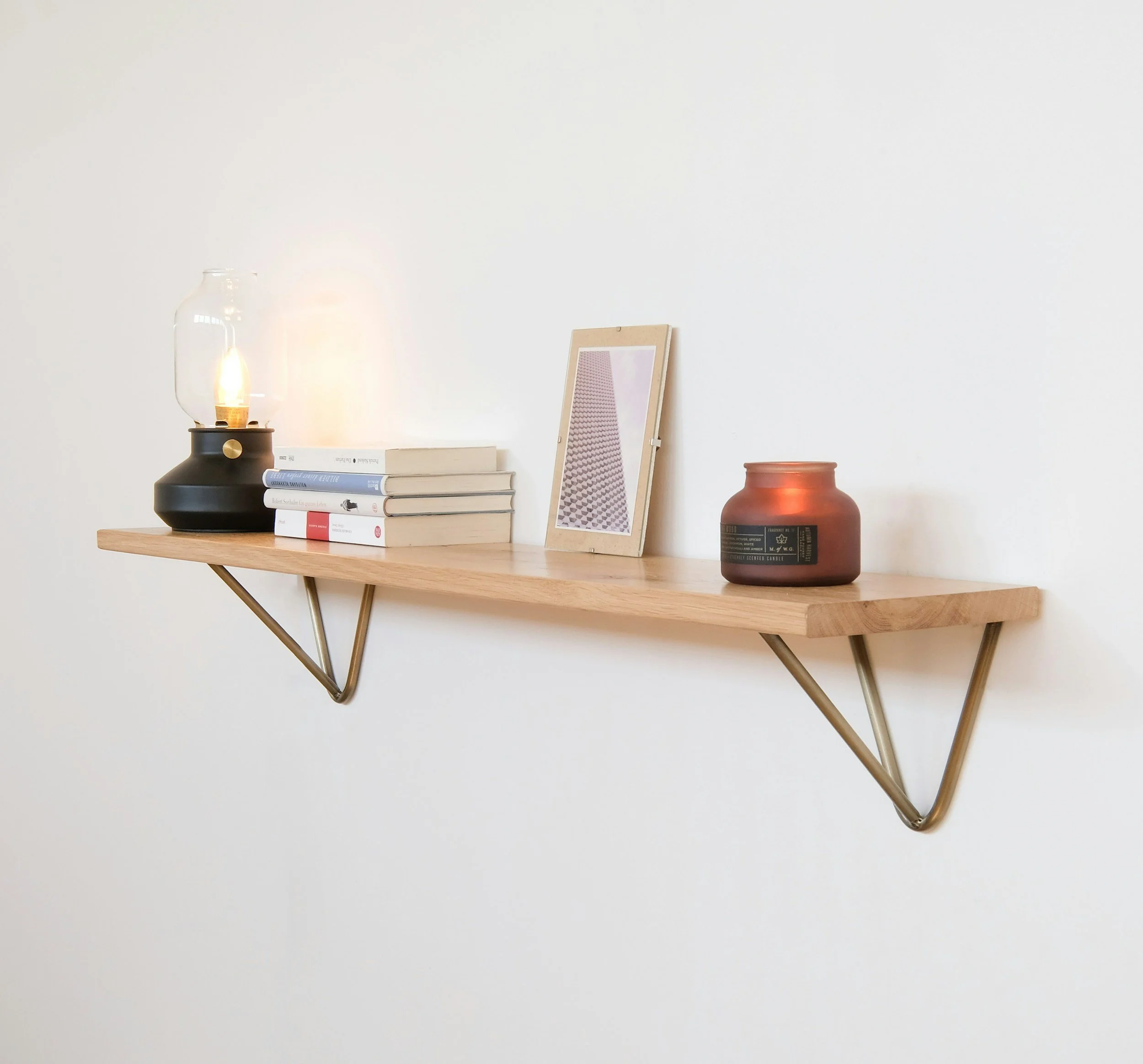 wood floating shelf with books and a candle