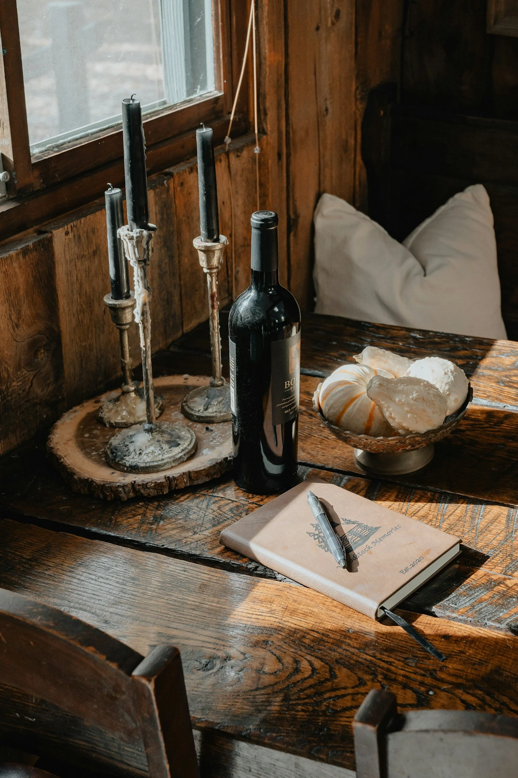 wine bottle and vintage candle holders with dark candles on a wood table