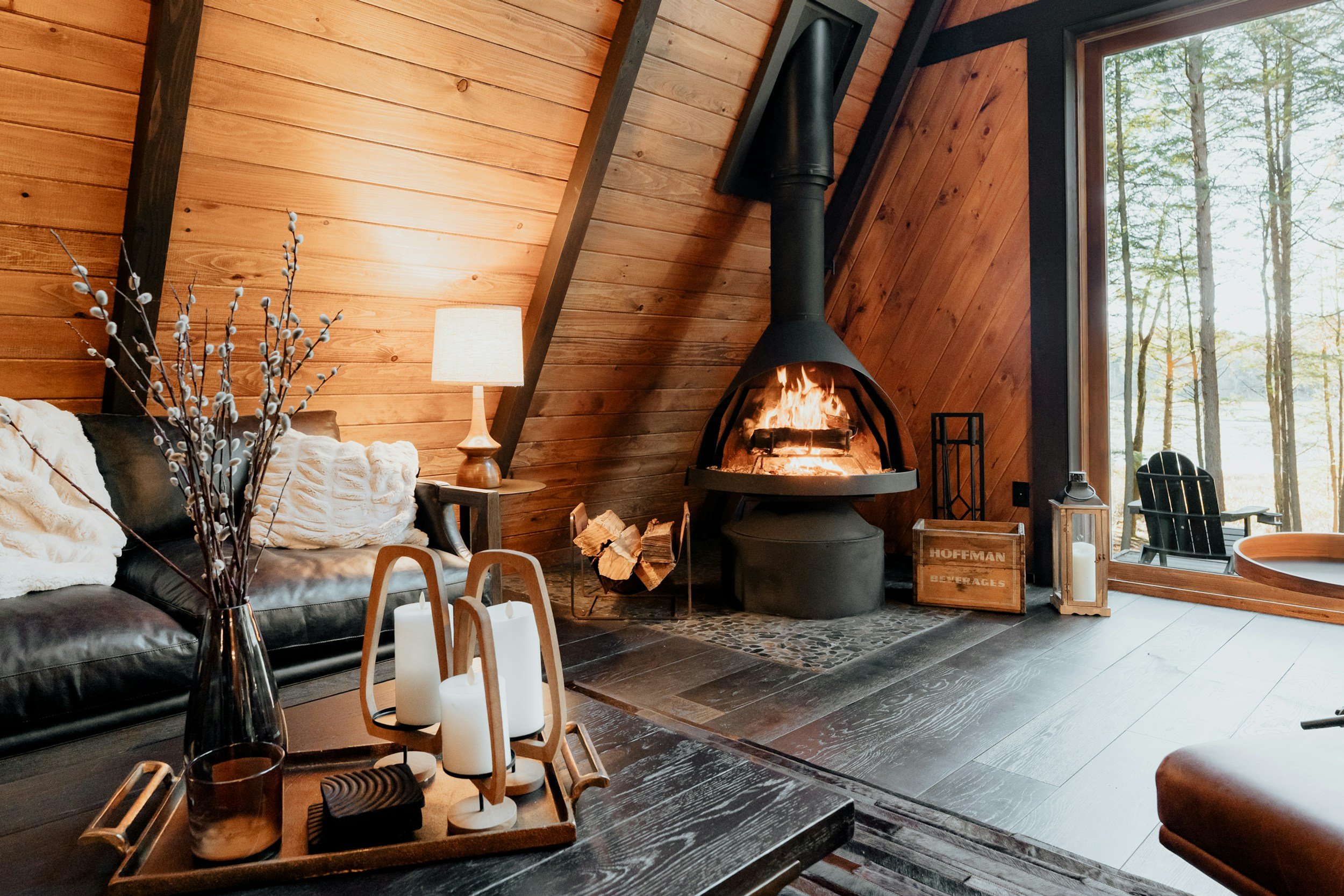 wood cabin with wood burning fireplace and black leather sofa
