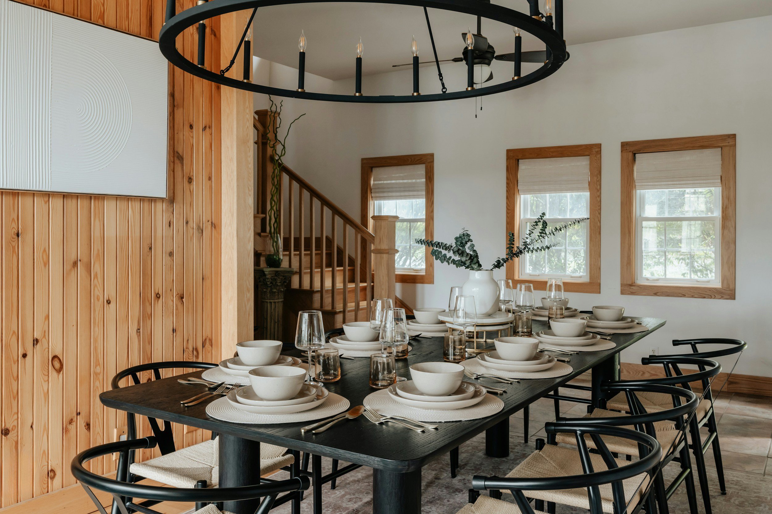 dining room with wagon wheel chandelier and wood walls
