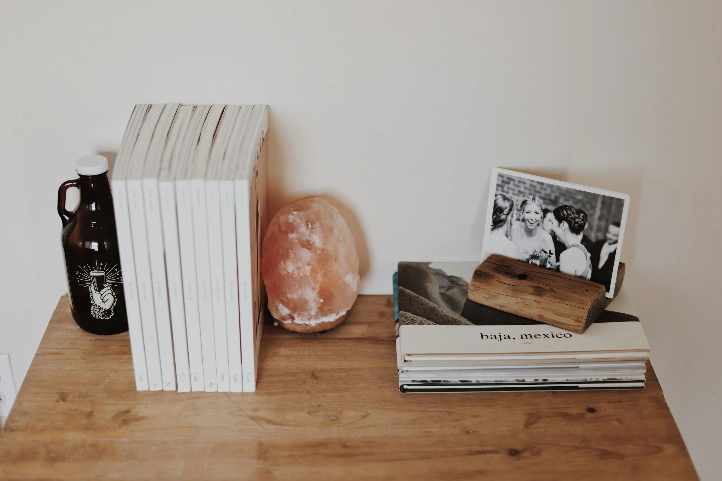 wood nightstand with books and a crystal